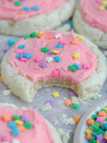 A bite cascades through the pink delicious frosting and into a crispy sugar cookie.