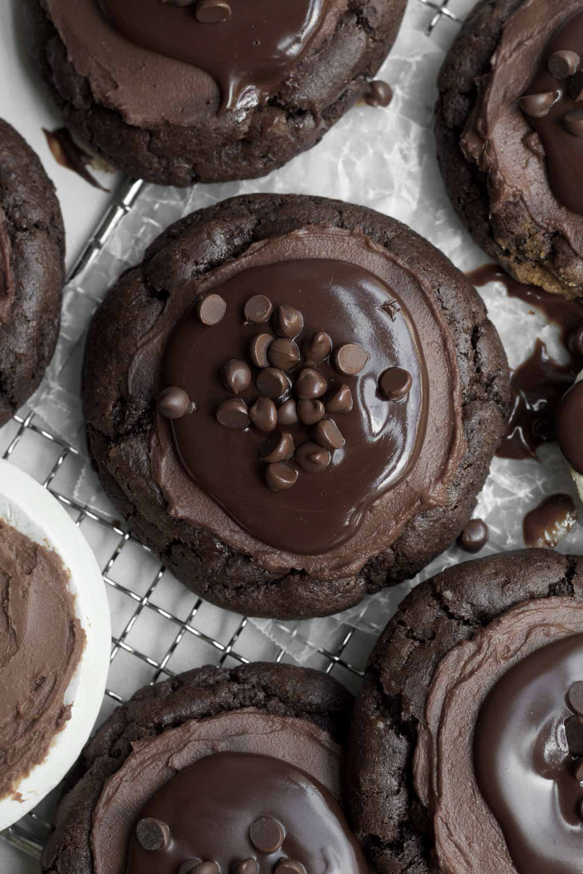 Shiny chocolate ganache topped with chocolate chips on chocolate cheesecake cookies.