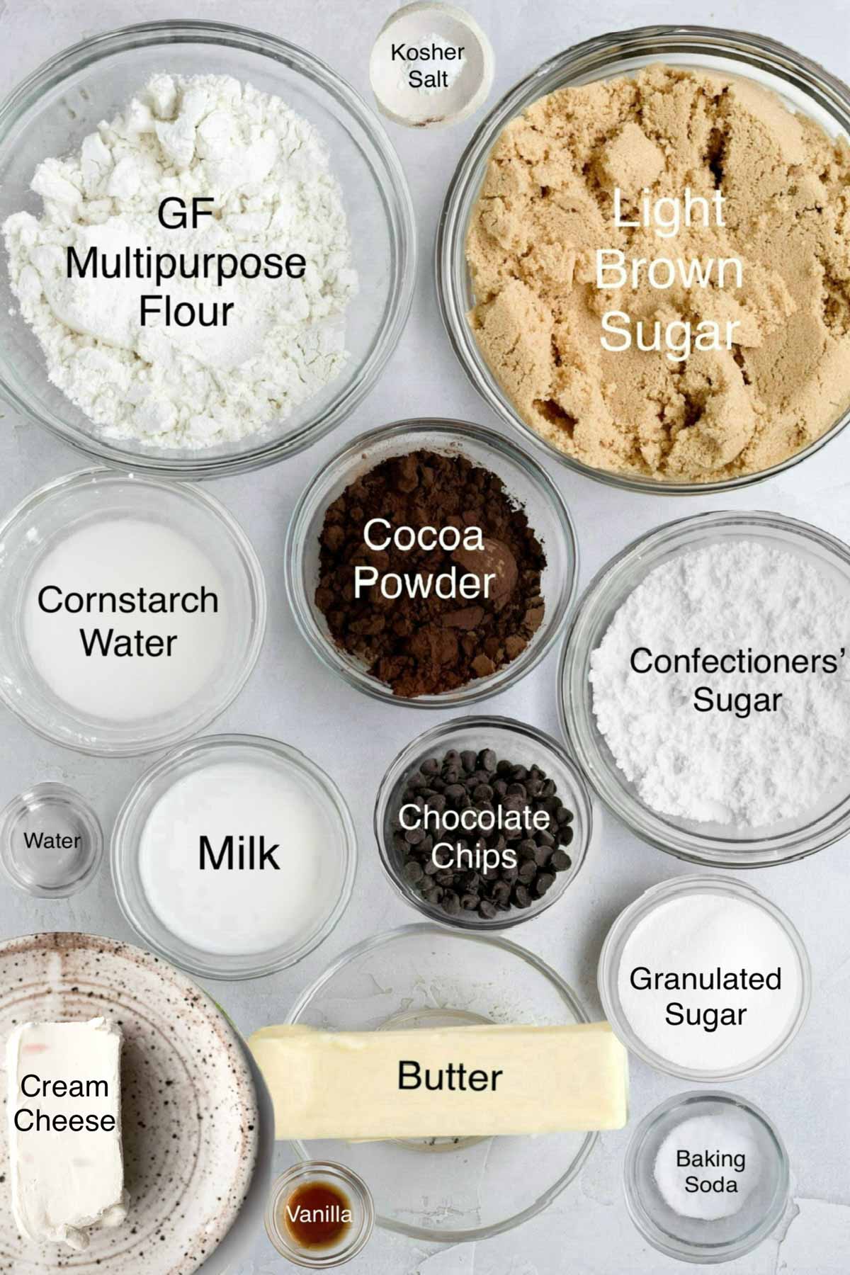 Bowls of gluten free multipurpose flour, kosher salt, light brown sugar, cornstarch water, cocoa powder, confectioners' sugar, water, milk, chocolate chips, granulated sugar, cream cheese, butter, granulated sugar, vanilla and baking soda.