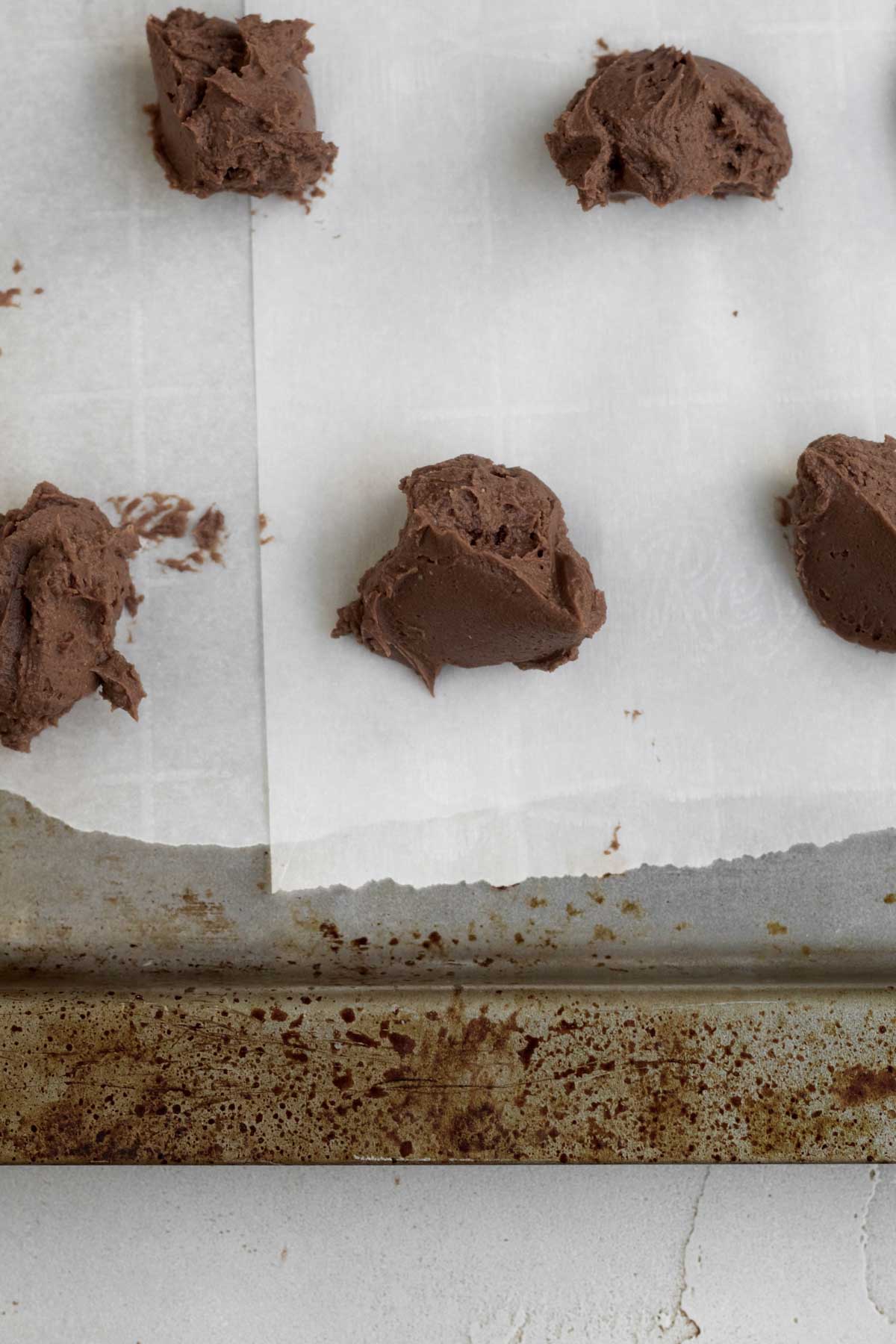 Dollops of chocolate cheesecake filling on parchment paper.