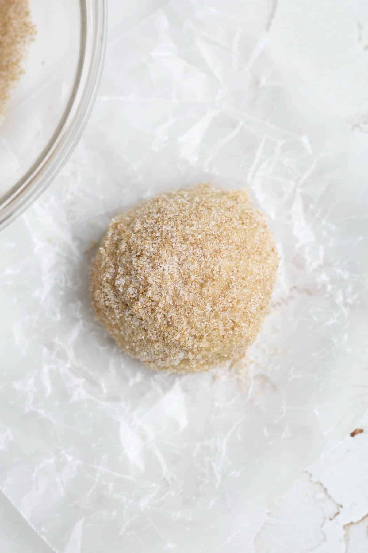 Coating the brown sugar maple dough ball with cinnamon sugar.
