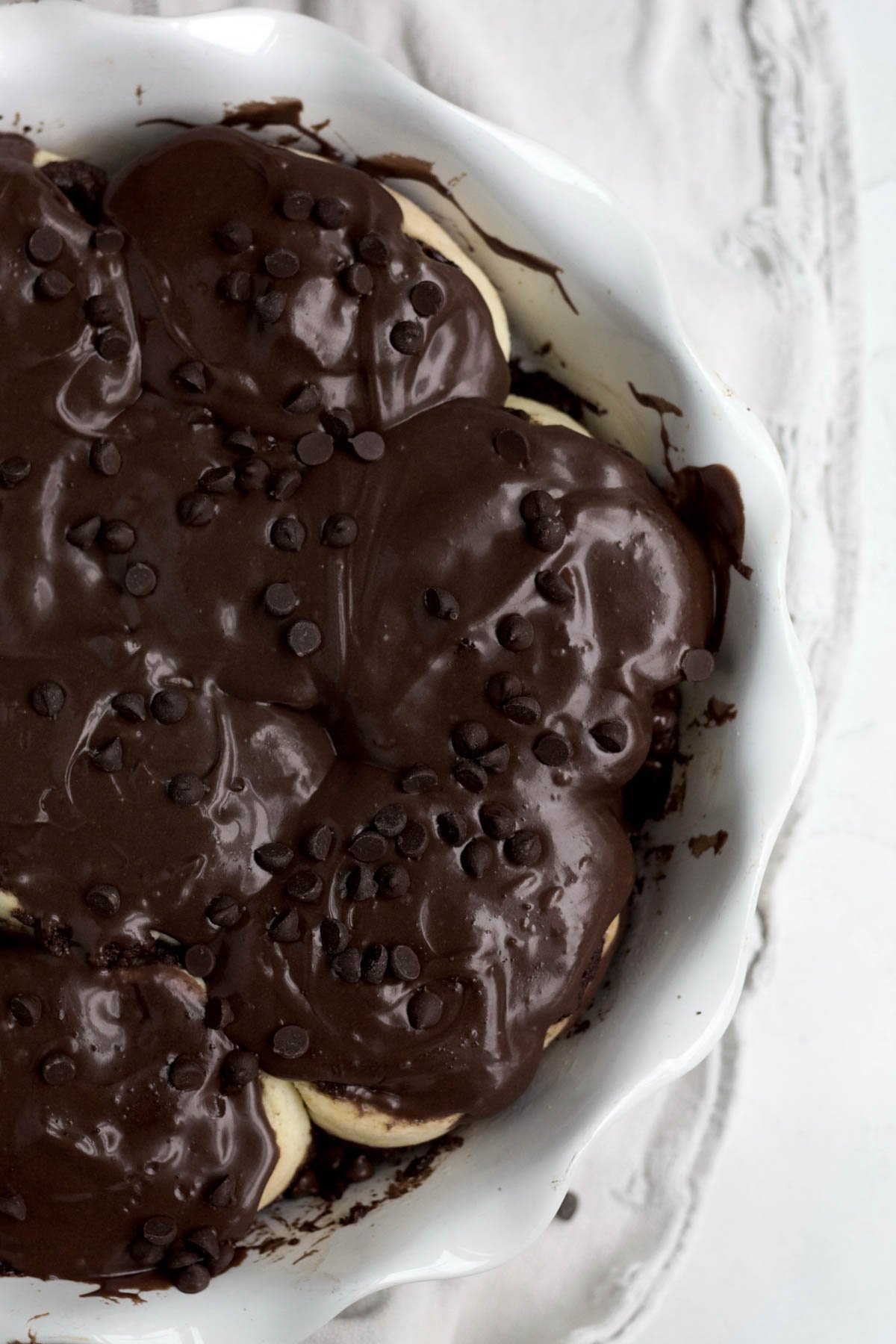 Topping the Chocolate and Cinnamon Rolls with the sugary glaze and chocolate chips.