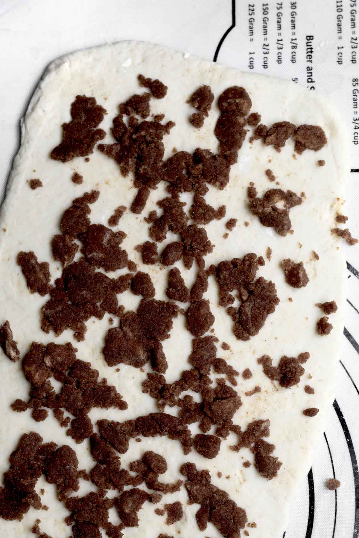 Sprinkling the cinnamon roll filling onto it.