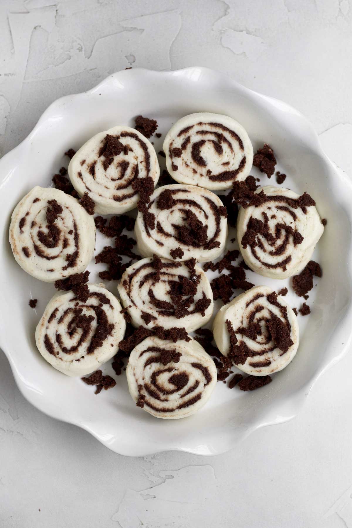 Slicing up the rolled up dough, placing it in a baking dish and sprinkling more filling.