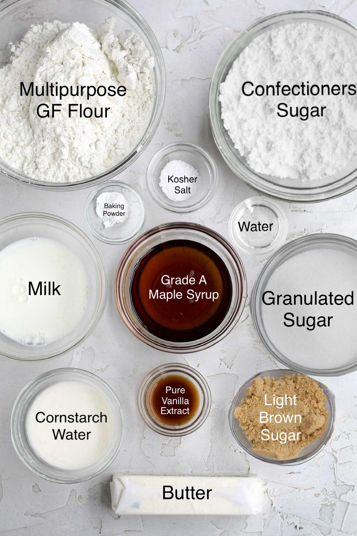 Bowls of multipurpose gluten free flour, confectioners' sugar, baking powder, kosher salt, water, milk, grade a maple syrup, granulated sugar, cornstarch water, pure vanilla extract, light brown sugar, and butter.
