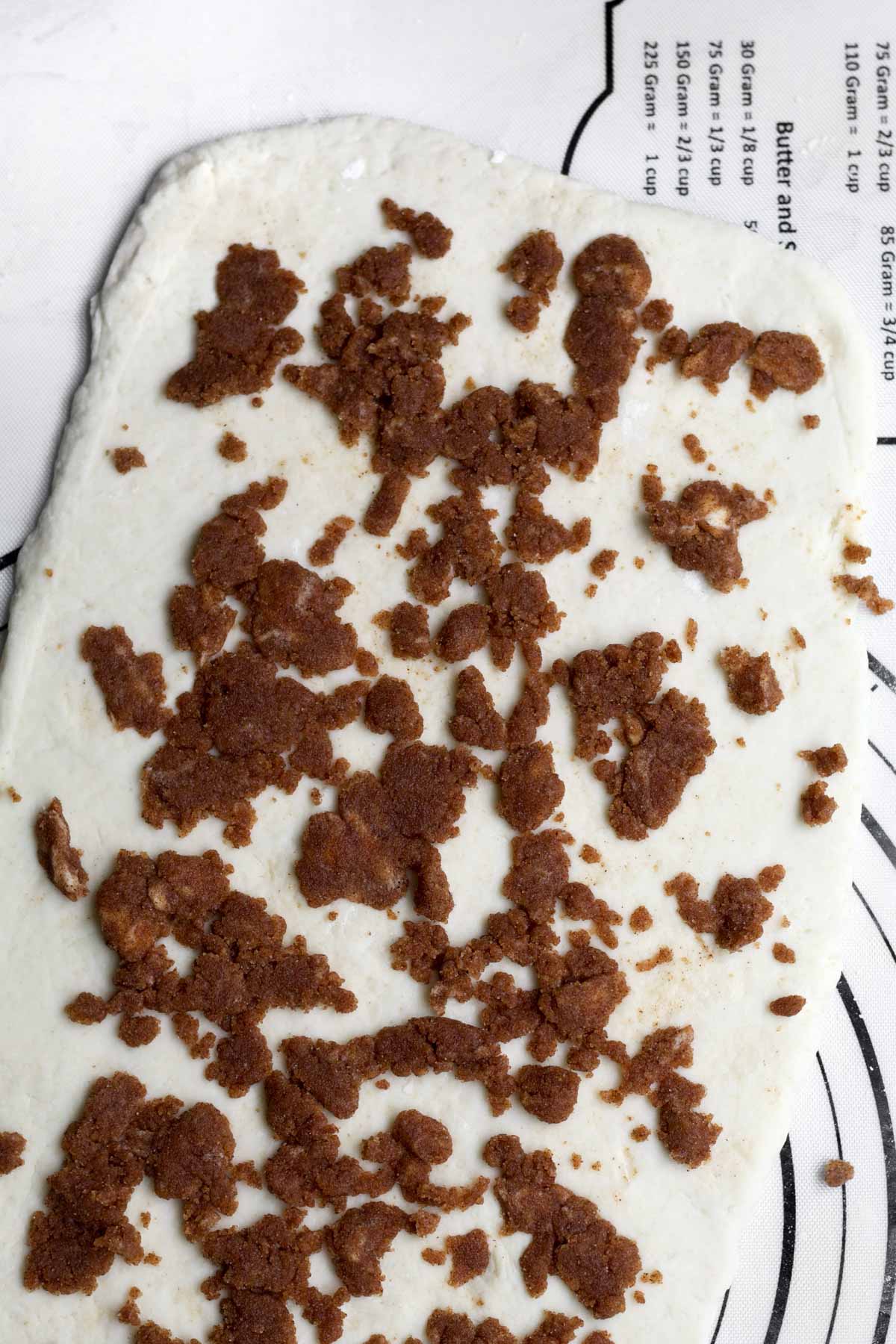 Sprinkling the cinnamon roll filling onto it.