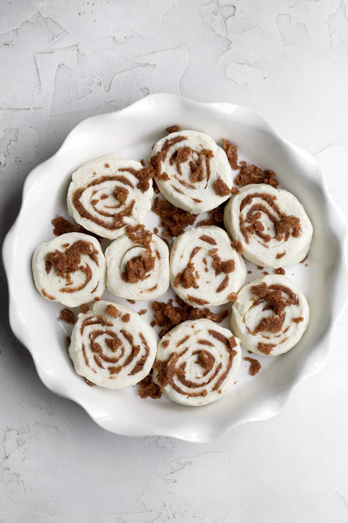 Slicing up the rolled up dough, placing it in a baking dish and sprinkling more filling.