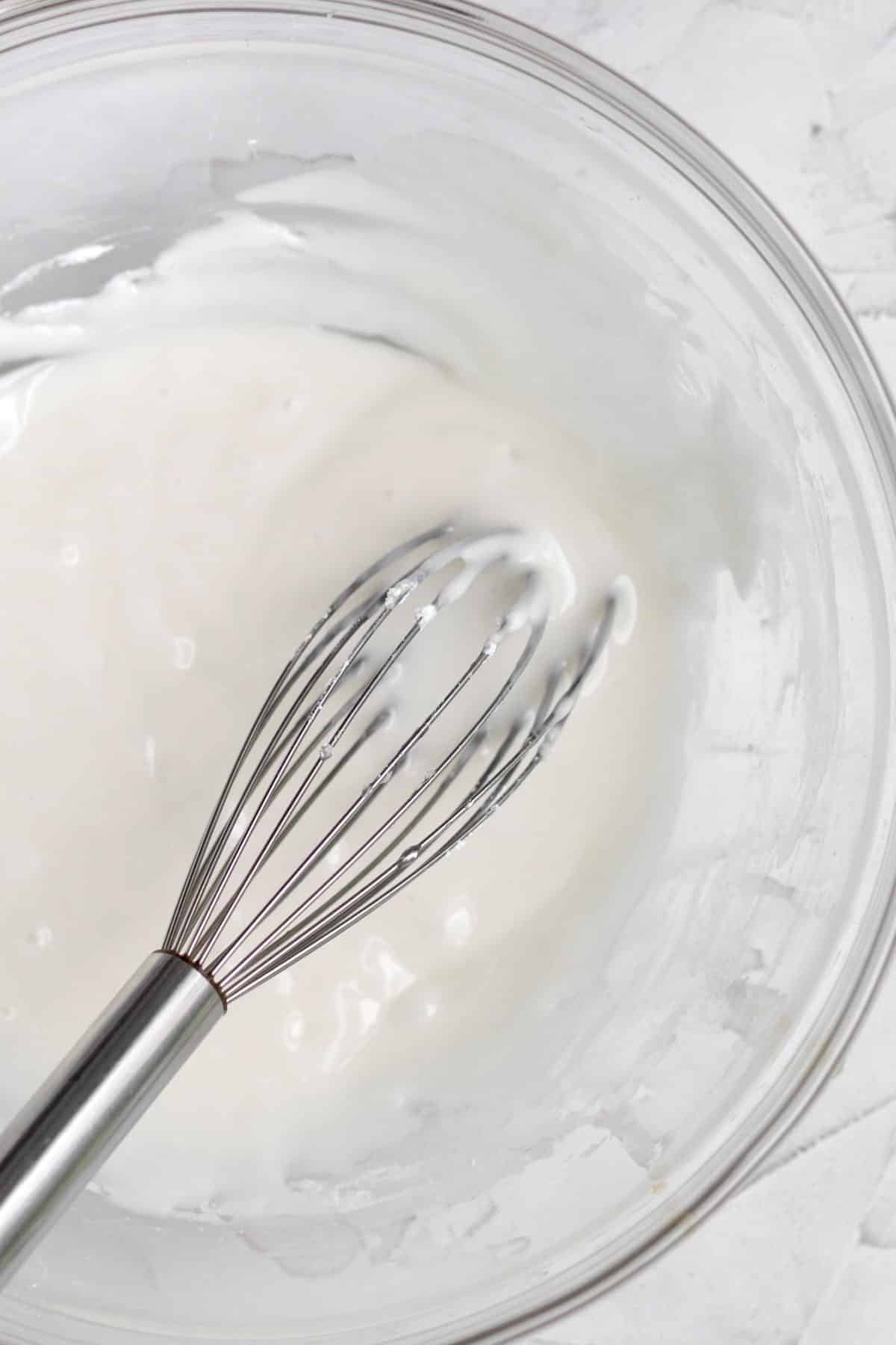 Whisking together the confectioners' sugar, corn syrup, vanilla, salt and water to make the vanilla icing.