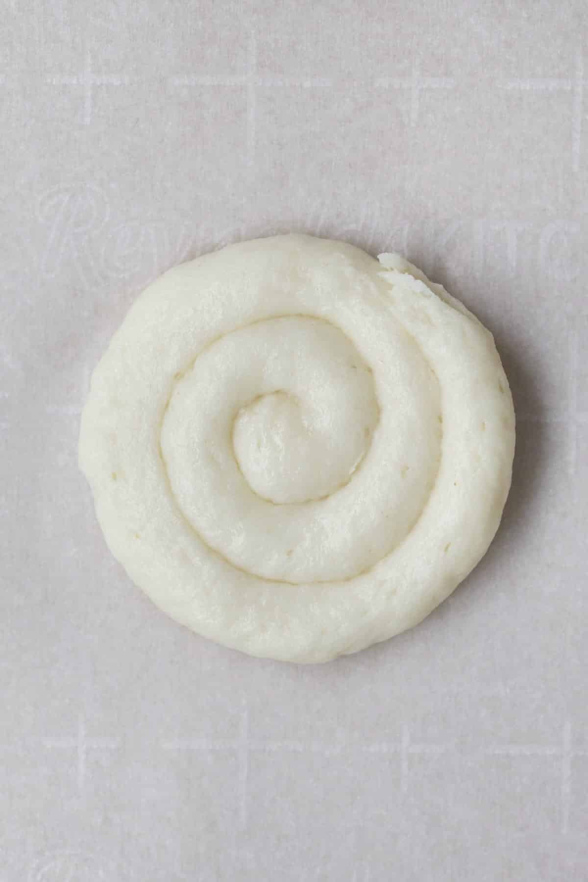 Piping a closed circular swirl of cookie dough batter.