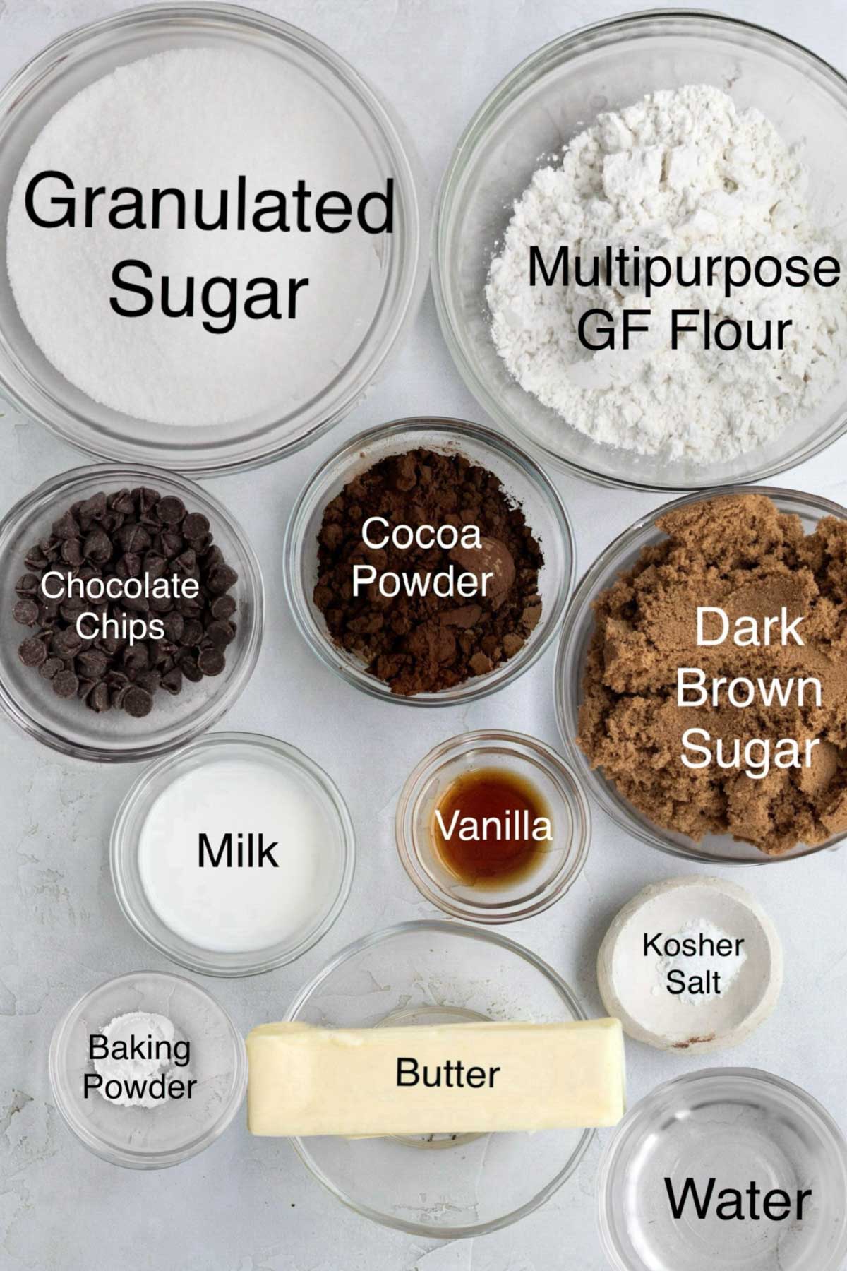 Bowls of granulated sugar, multipurpose gluten free flour, chocolate chips, cocoa powder, dark brown sugar, milk, vanilla, kosher salt, baking powder, butter and water.