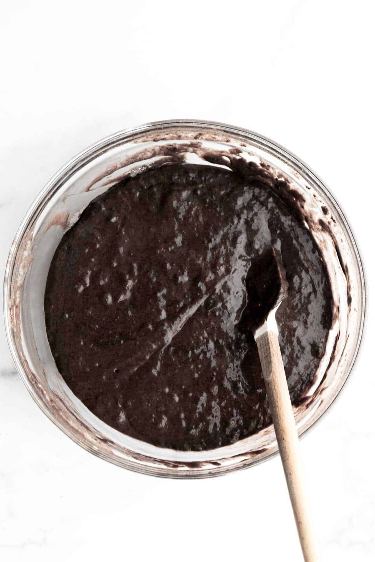 Stirring the wet ingredients in with a spatula into chocolate cupcake batter.