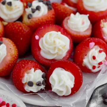 Juicy Cheesecake Stuffed Strawberries topped with chocolate chips, heart sprinkles and graham cracker.
