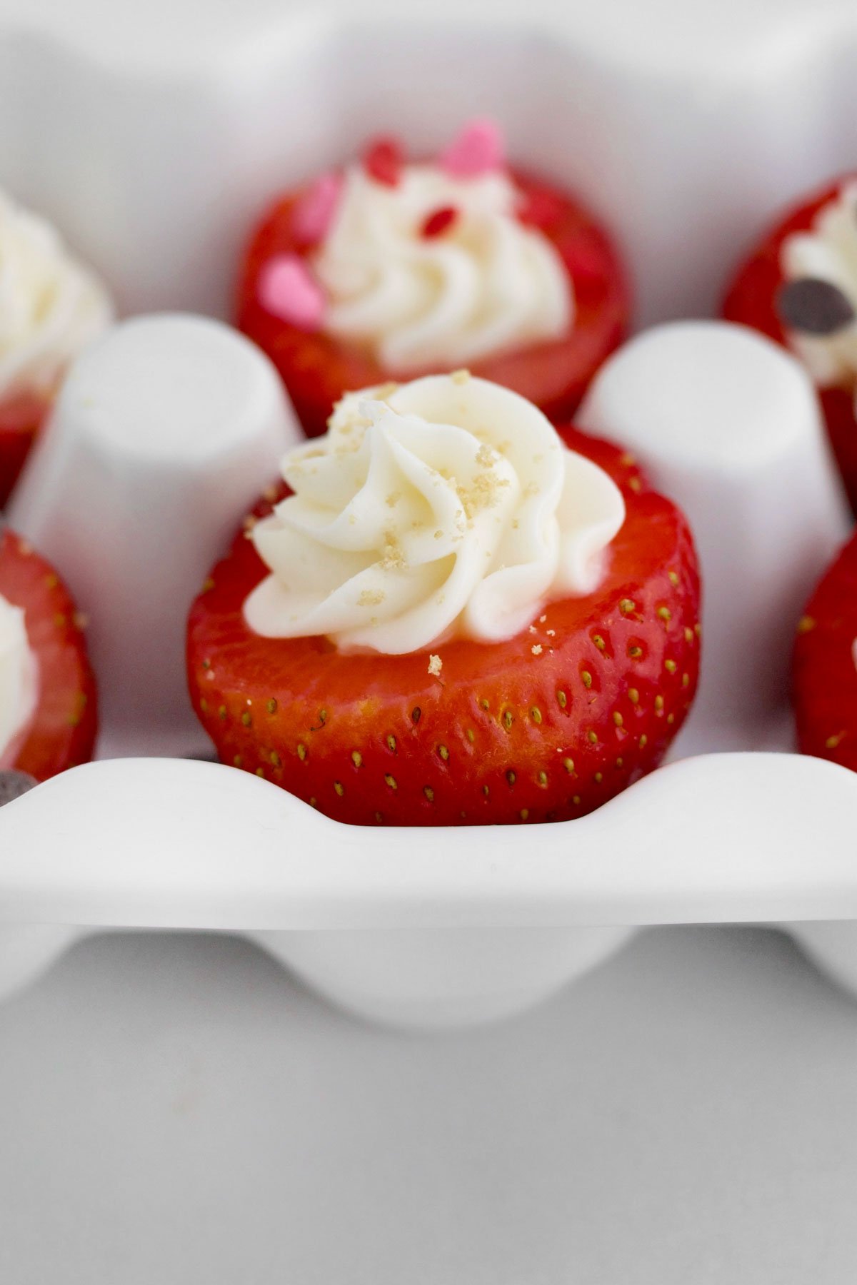 And egg carton holds the fresh Cheesecake Stuffed Strawberries with graham cracker crumbs