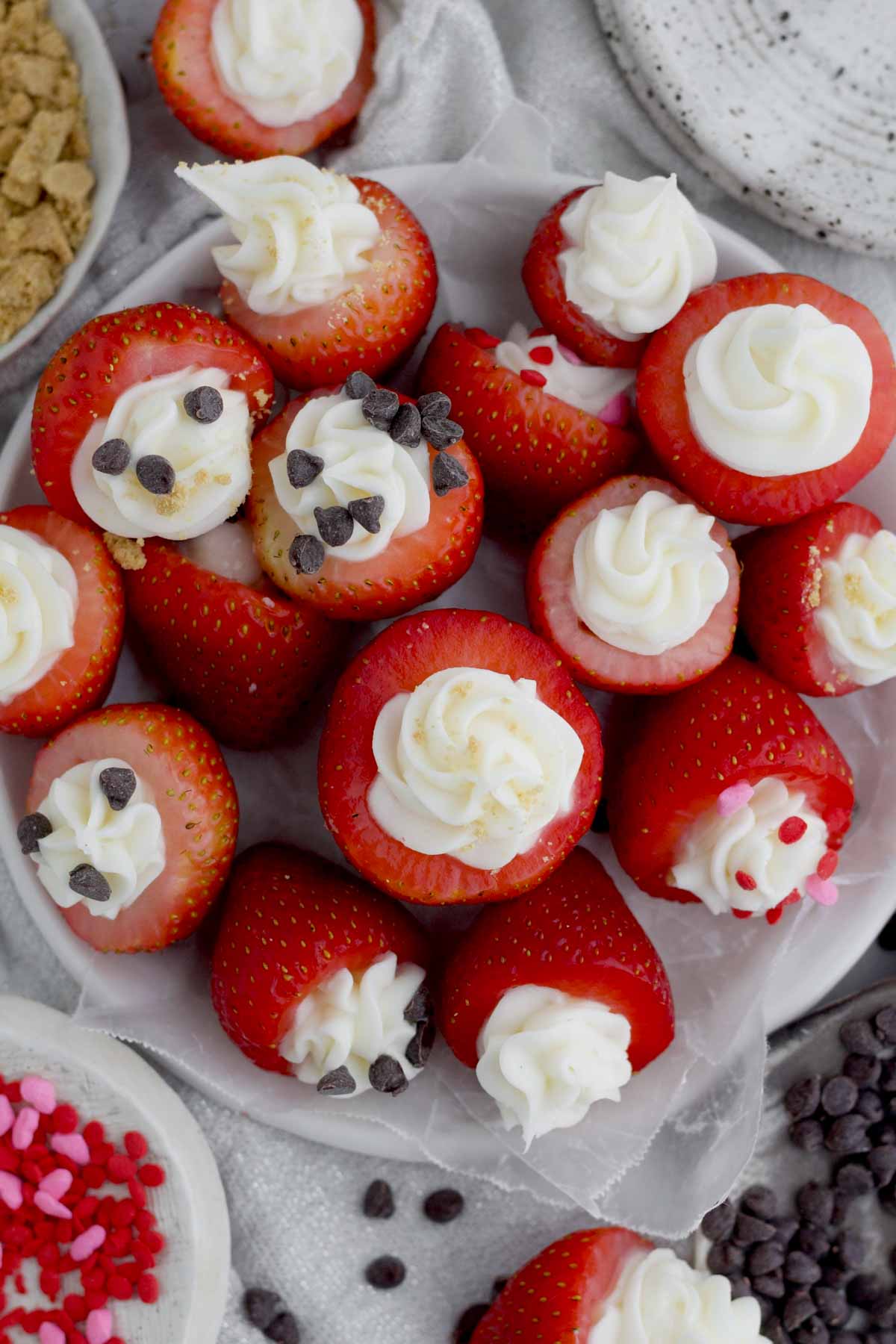 No Bake Cheesecake Stuffed Strawberries dessert arranged overcrowding a plate with festive toppings.