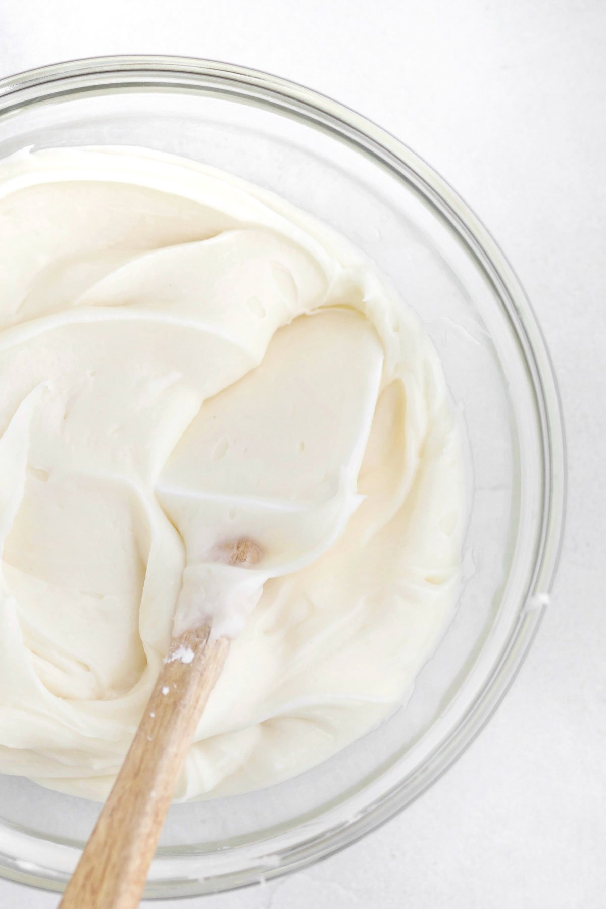 Silky smooth cream cheese frosting in a bowl with a spatula.