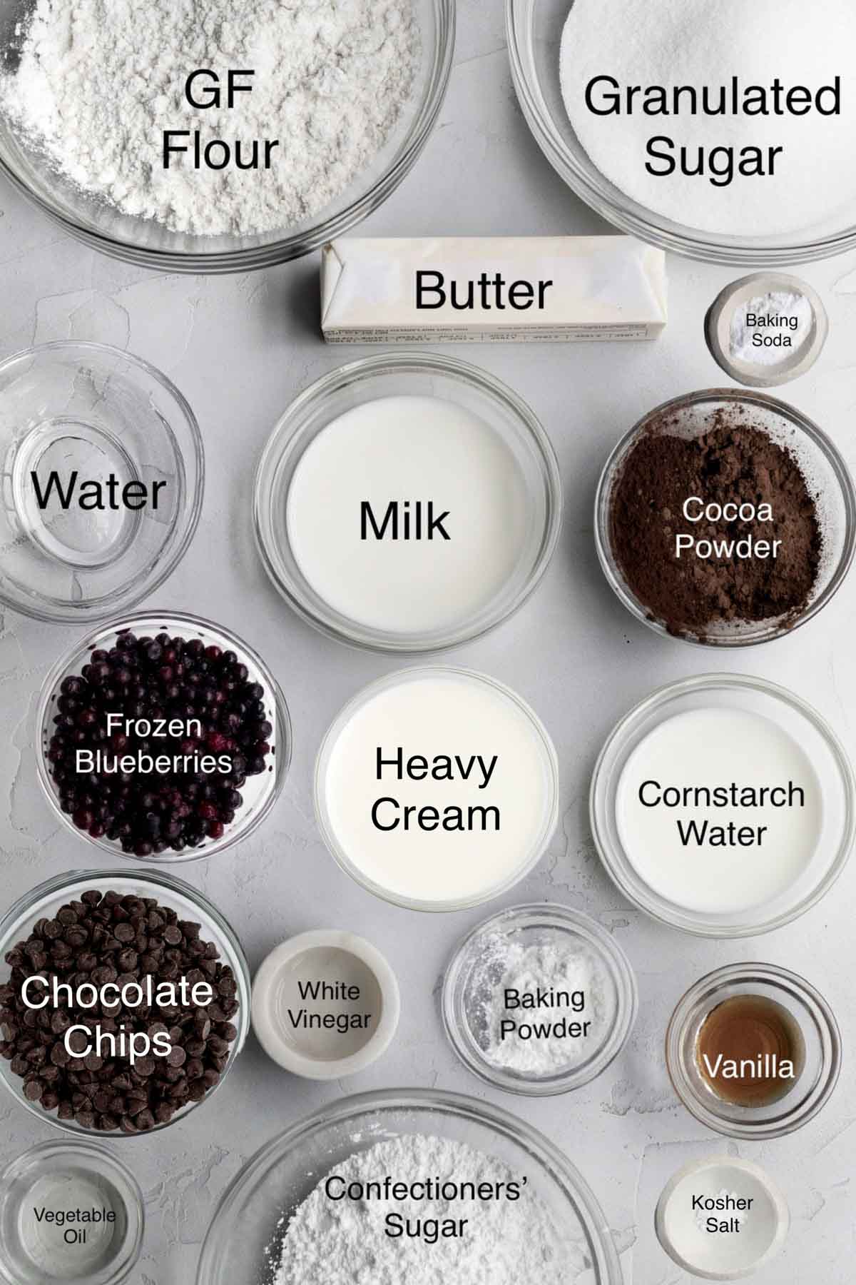 Chocolate blueberry cake ingredients: gluten free flour, granulated sugar, butter, water, milk, baking soda, cocoa powder, frozen blueberries, heavy cream, cornstarch water, chocolate chips, white vinegar, baking powder, vanilla, vegetable oil, confectioners' sugar, and kosher salt