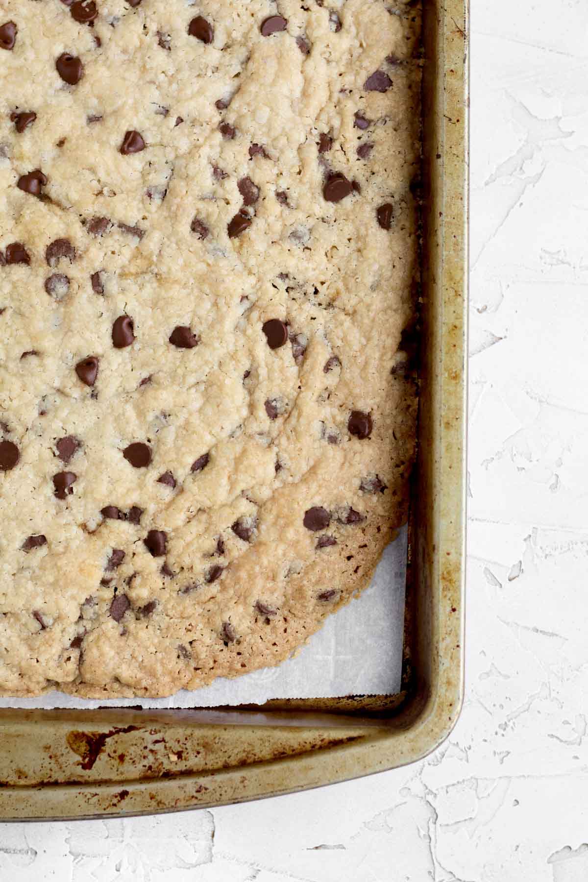 Golden baked cookie brittle in the baking sheet dotted with melted chocolate chips.