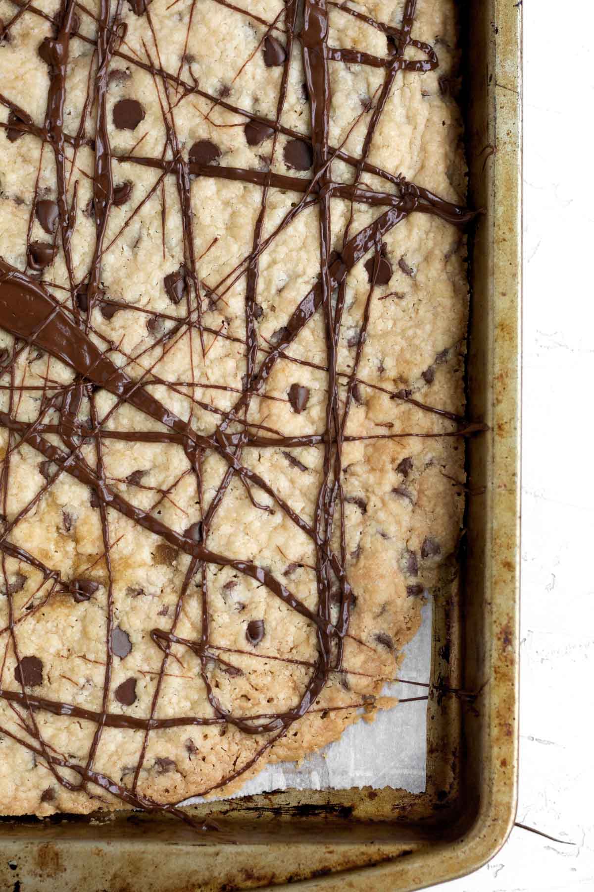 Rich melted chocolate is drizzled in a reckless crosshatch pattern atop the baked cookie brittle sheet.