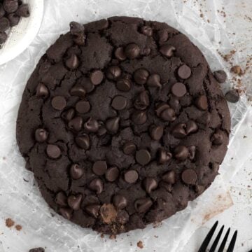 Homemade decadent Giant Chocolate Cookie with rich chocolate chips on parchment paper.