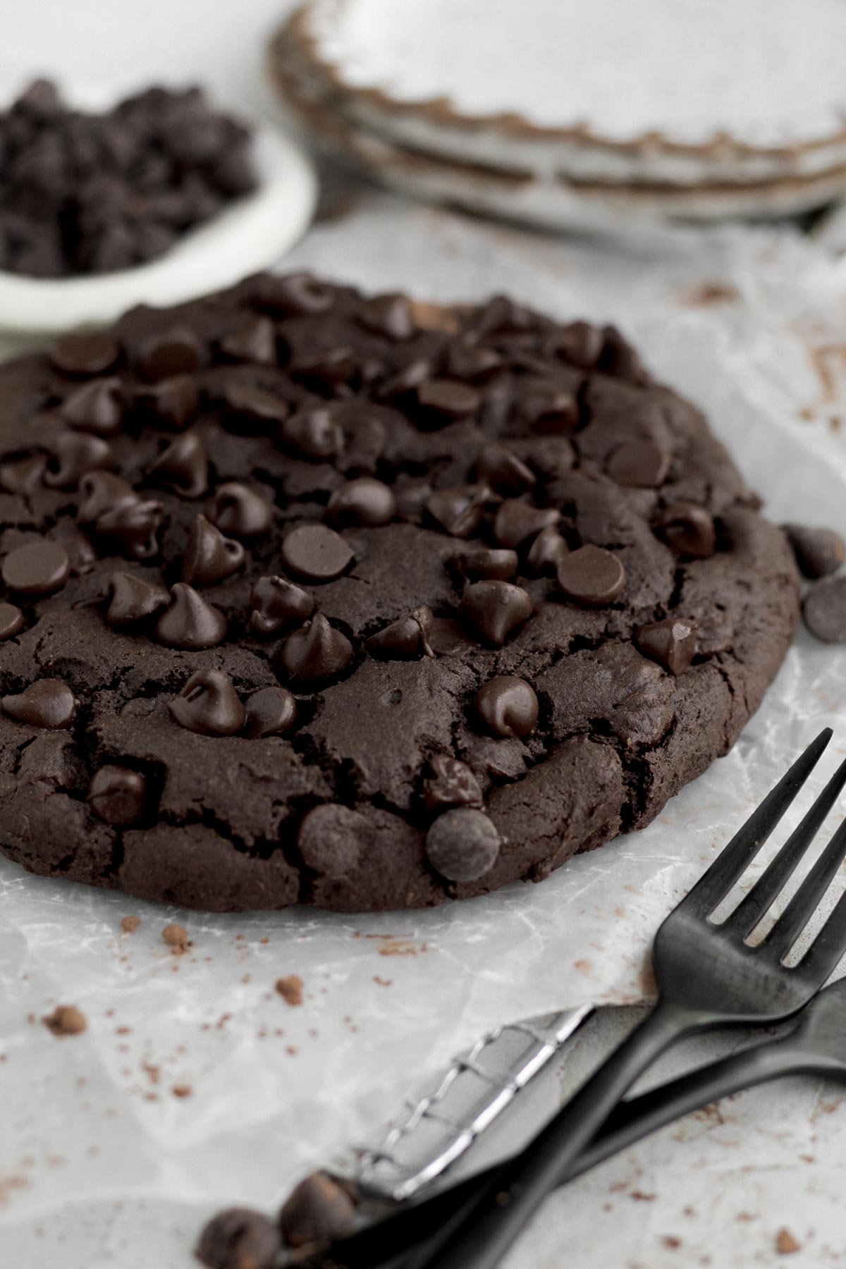 A fork is dwarfed by the Giant Chocolate Cookie sitting deliciously in the background.