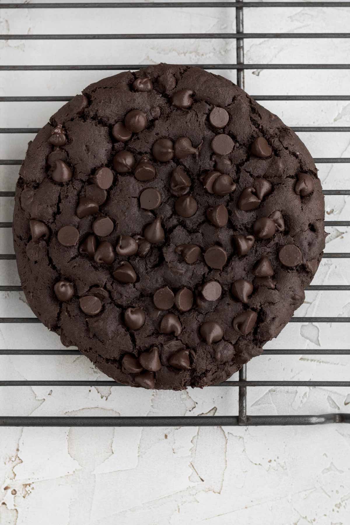Fresh baked Giant Chocolate Cookie resting on a cooling rack.