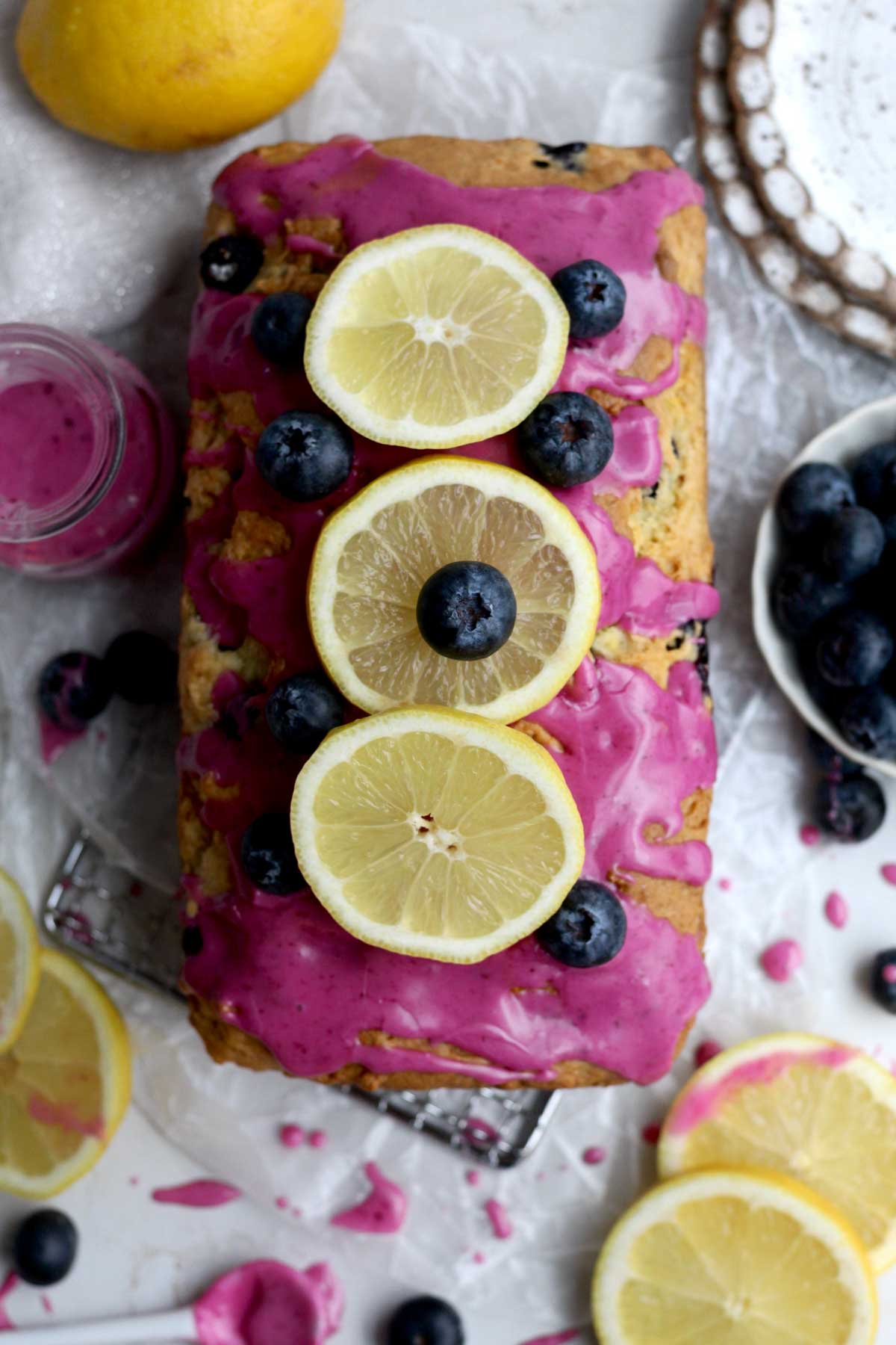 Gluten-free lemon blueberry loaf topped with fresh lemon slices, blueberry glaze, and juicy blueberries.