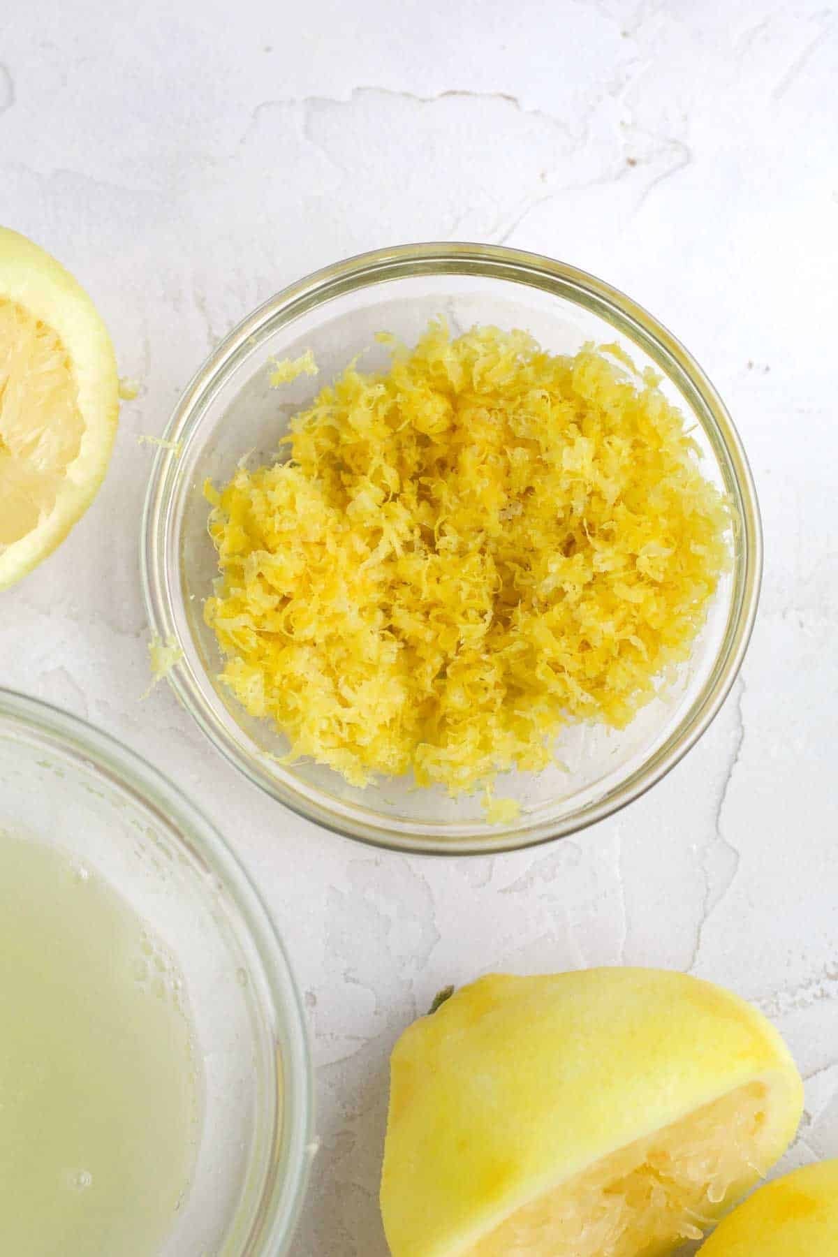 Bright yellow lemon zest and juice in bowls.