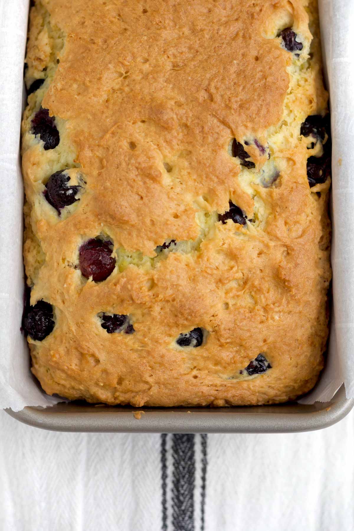 Fresh baked golden brown lemon blueberry loaf with bursted warm blueberries.