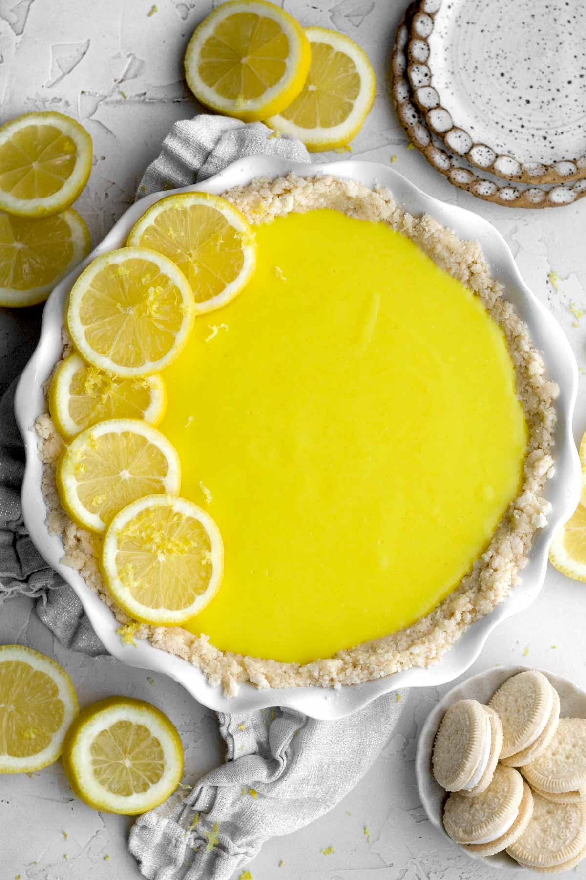 whole, vibrant lemon curd pie garnished with fresh lemon wedges in a ruffled pie dish.