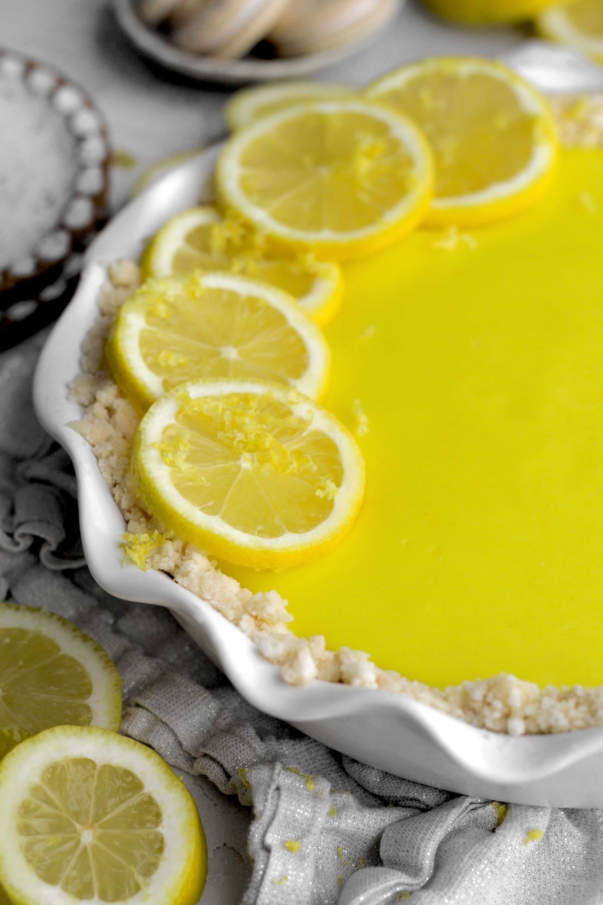round slices of lemon sit on a creamy lemon curd pie with a buttery cookie crust.