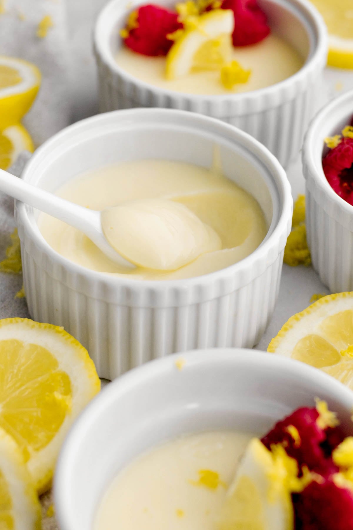 a white spoon scooping the sweet and creamy lemon posset from the ramekin.