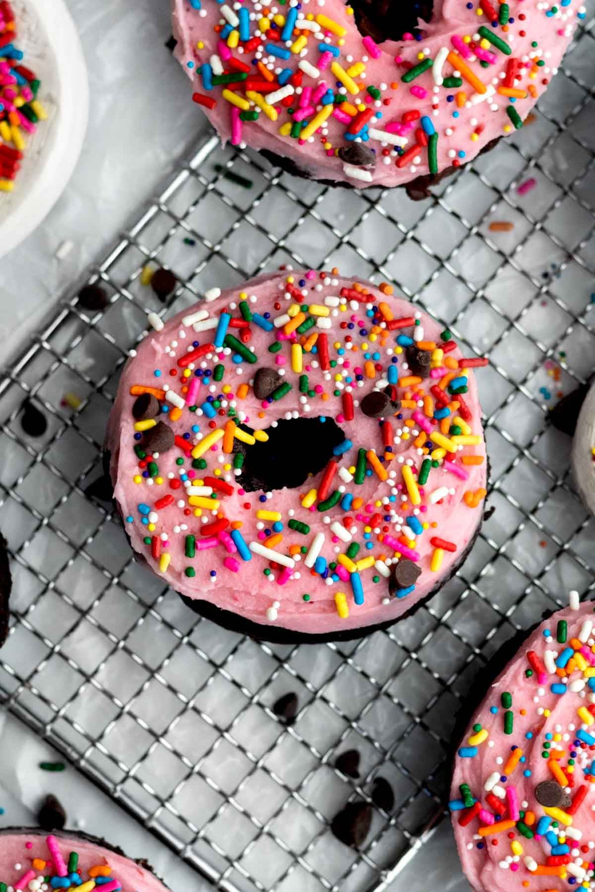 round happy birthday donut topped with sprinkles and creamy, tart, raspberry buttercream frosting.