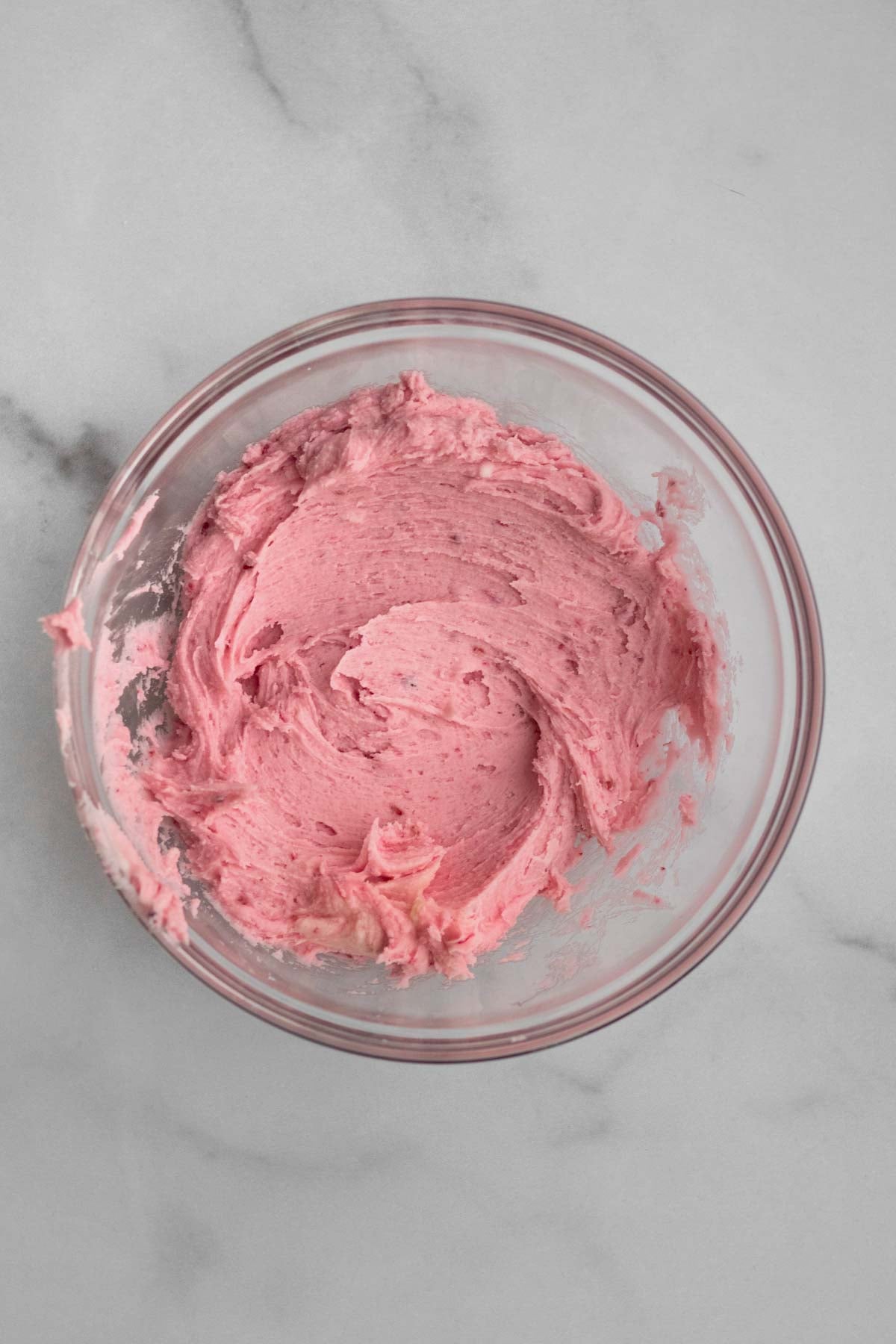 a creamy pink swirl of raspberry buttercream in a bowl.