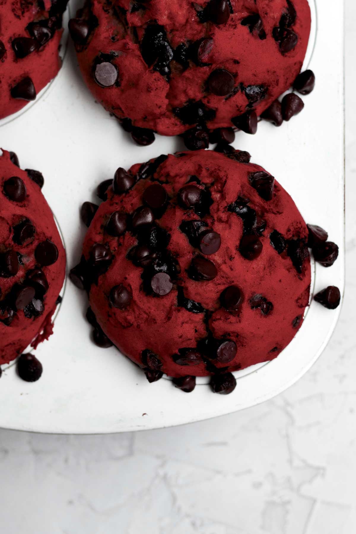 fresh-baked, warm red velvet muffins risen in the muffin tin.