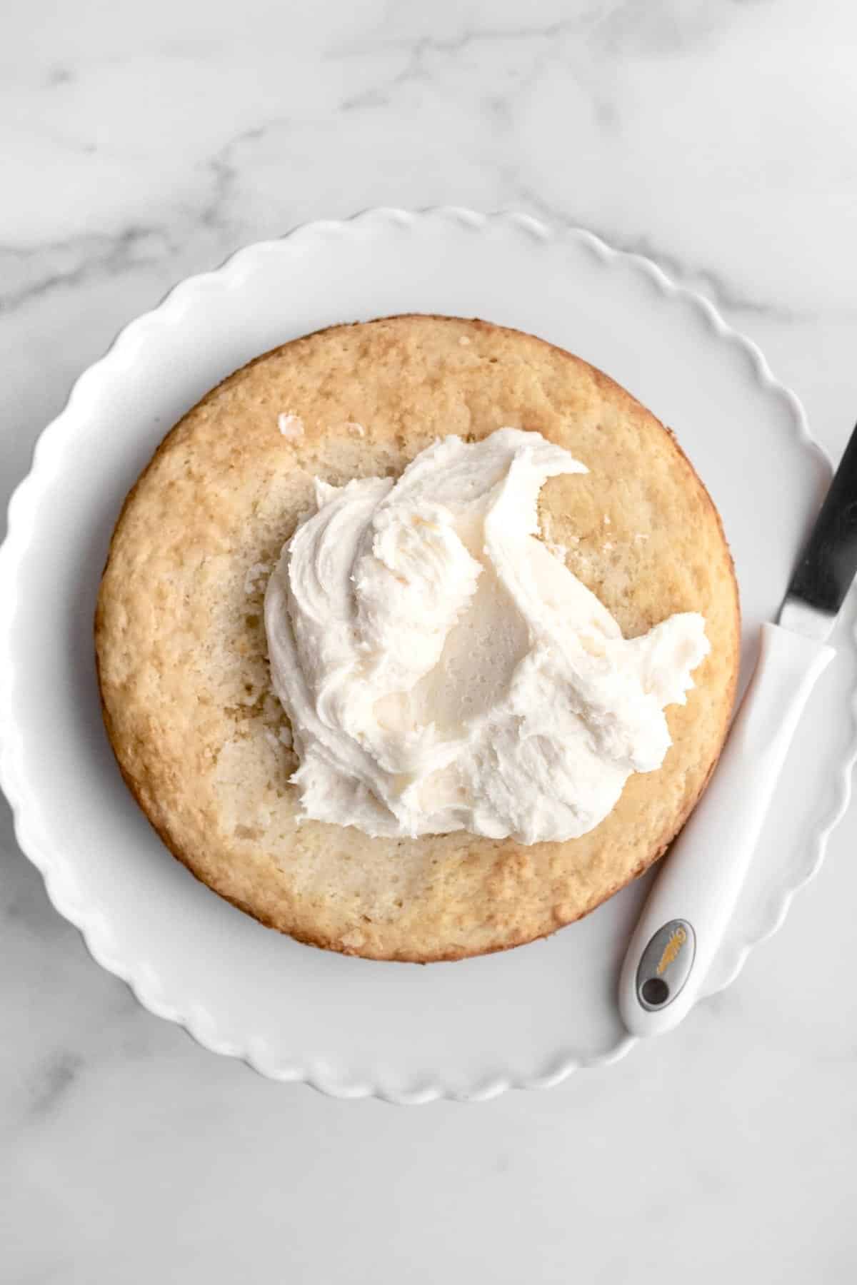 Spreading the creamy vanilla frosting on the vanilla cake.
