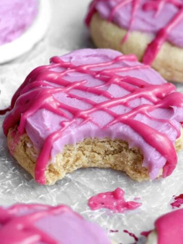 a bite reveals the tender brown sugar cookie beneath tangy blueberry cream cheese frosting and glaze.