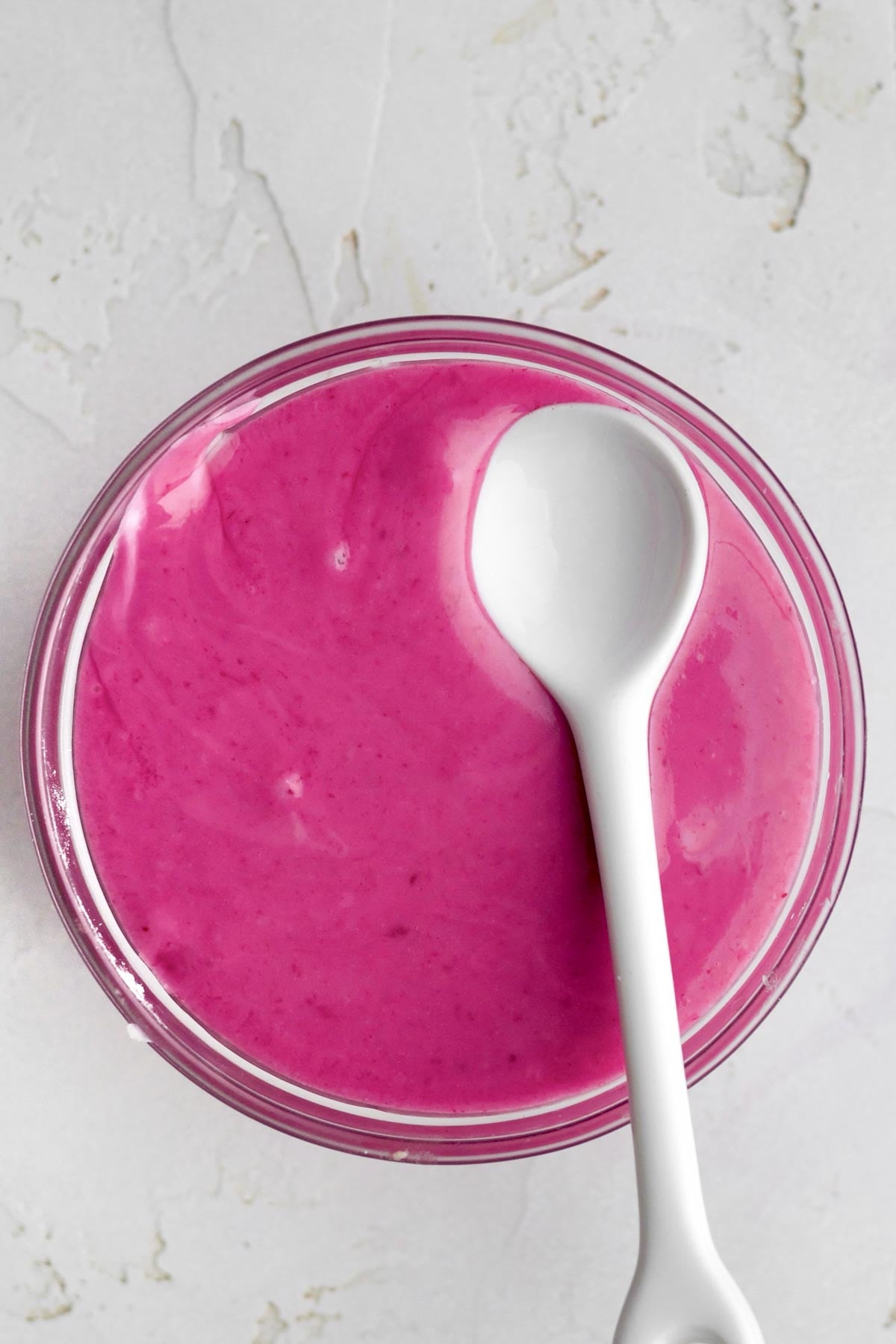 magenta blueberry icing in a small bowl with a spoon.