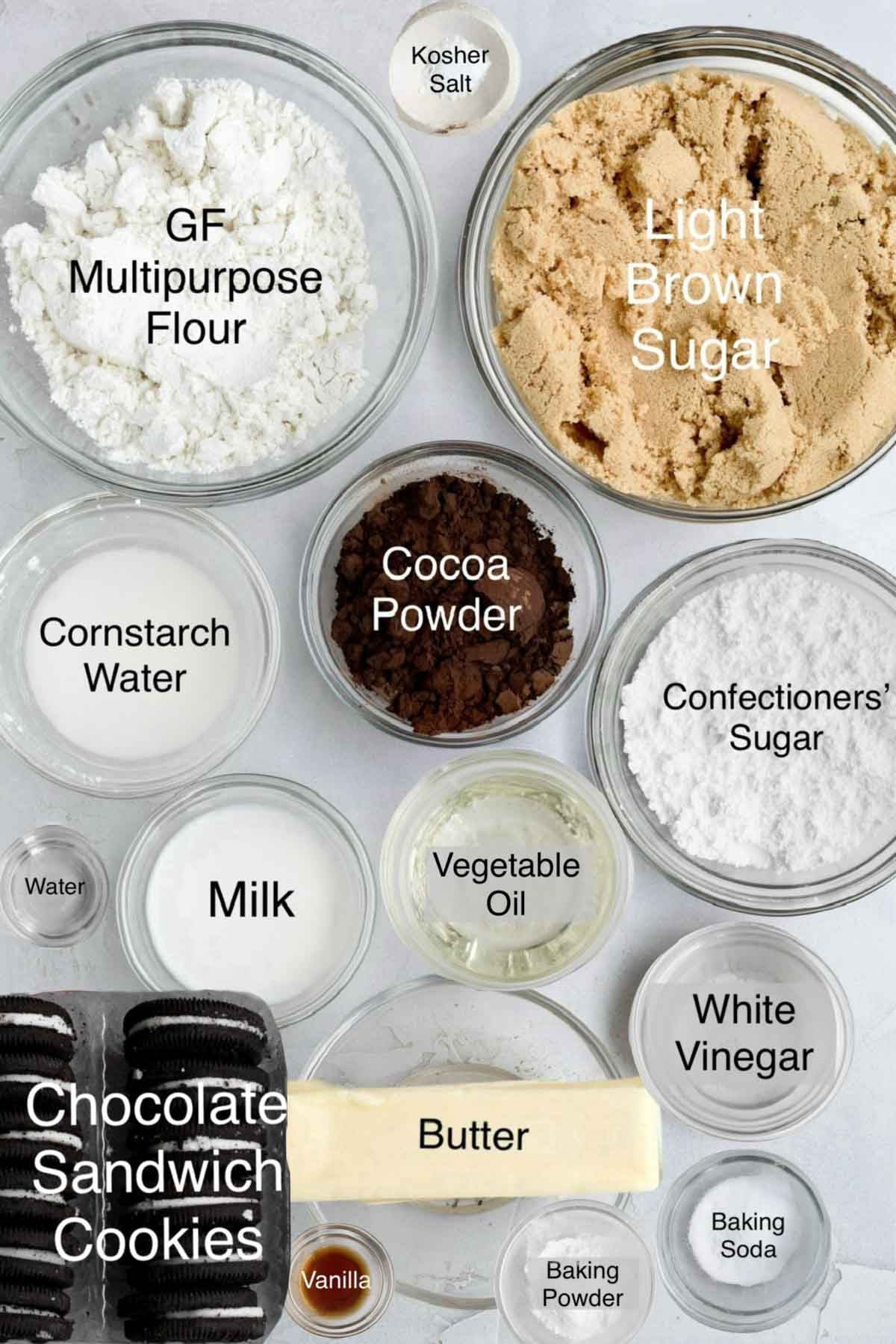 cookies and cream donuts ingredients in separate bowls: gluten free multipurpose flour, kosher salt, light brown sugar, cornstarch water, cocoa powder, confectioners' sugar, water, milk, vegetable oil, white vinegar, chocolate sandwich cookies, butter, white vinegar, vanilla, baking powder, and baking soda.