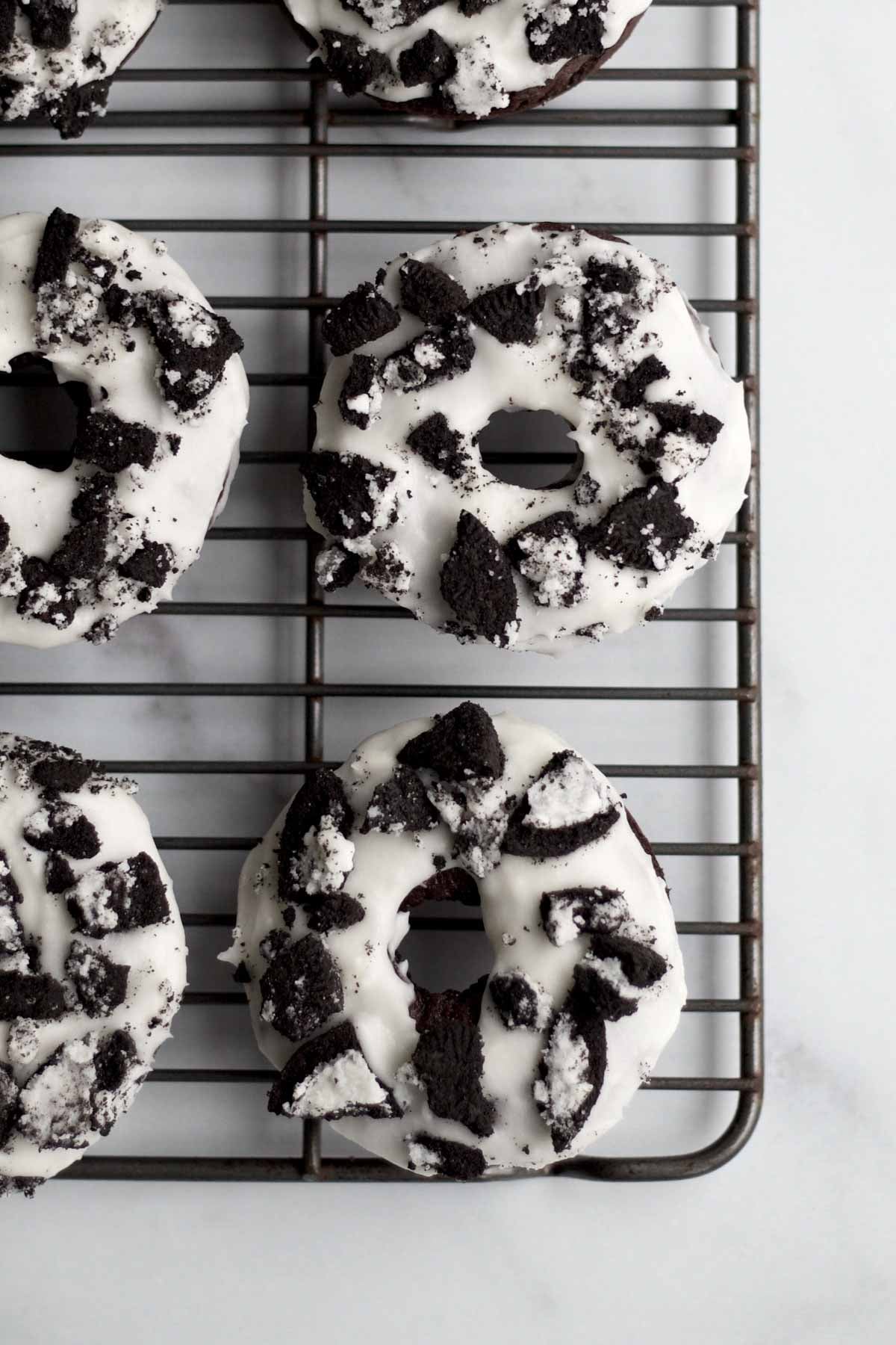topping the donuts with vanilla frosting and broken chocolate sandwich cookie.