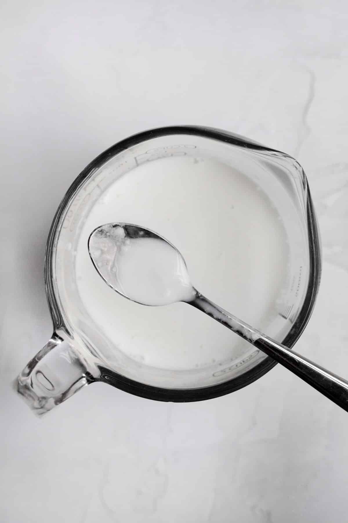 homemade buttermilk in a measuring cup with a spoon.