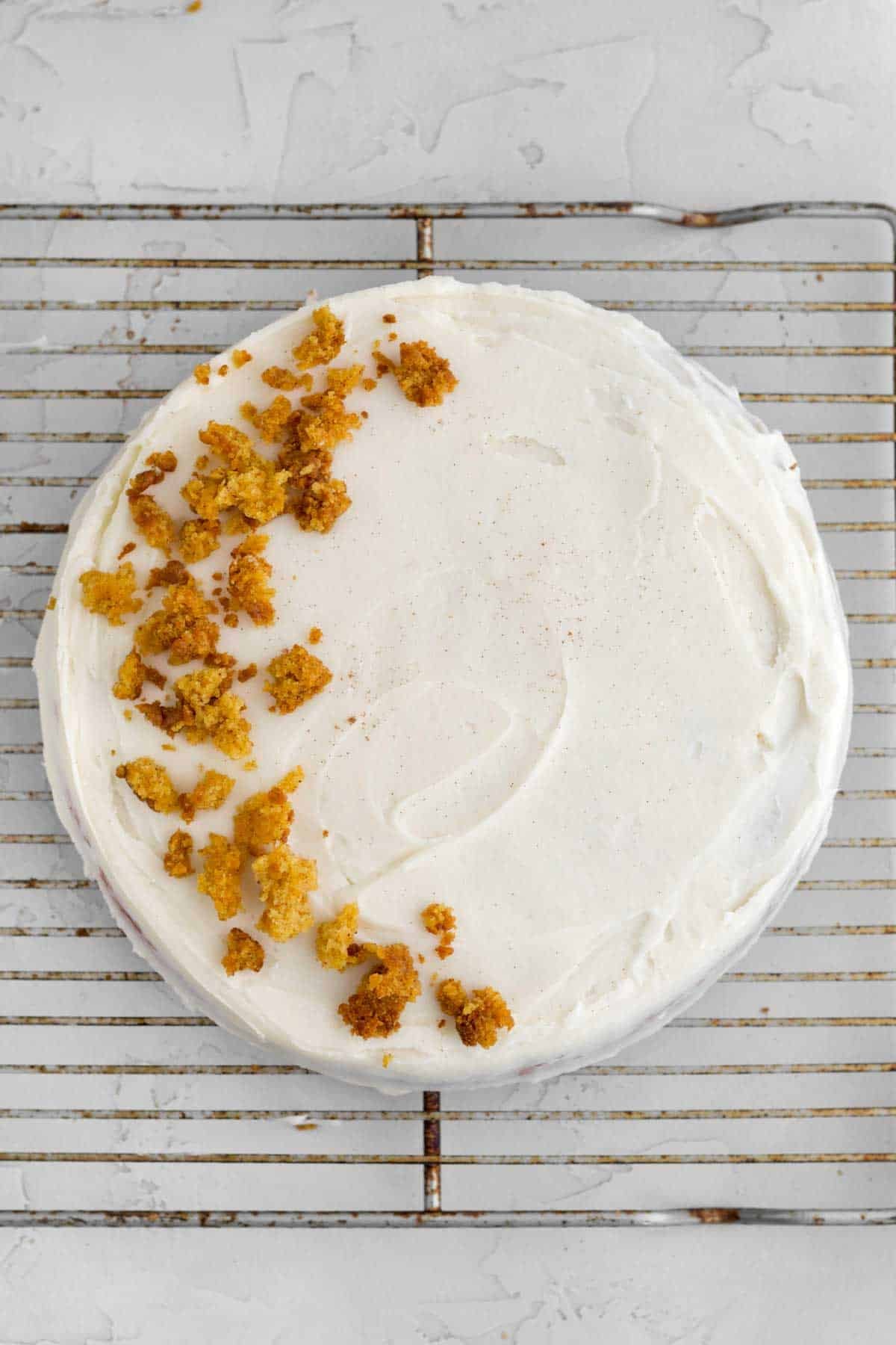 frosting the cake with cream cheese frosting and topping in a moon shape with cake crumbs