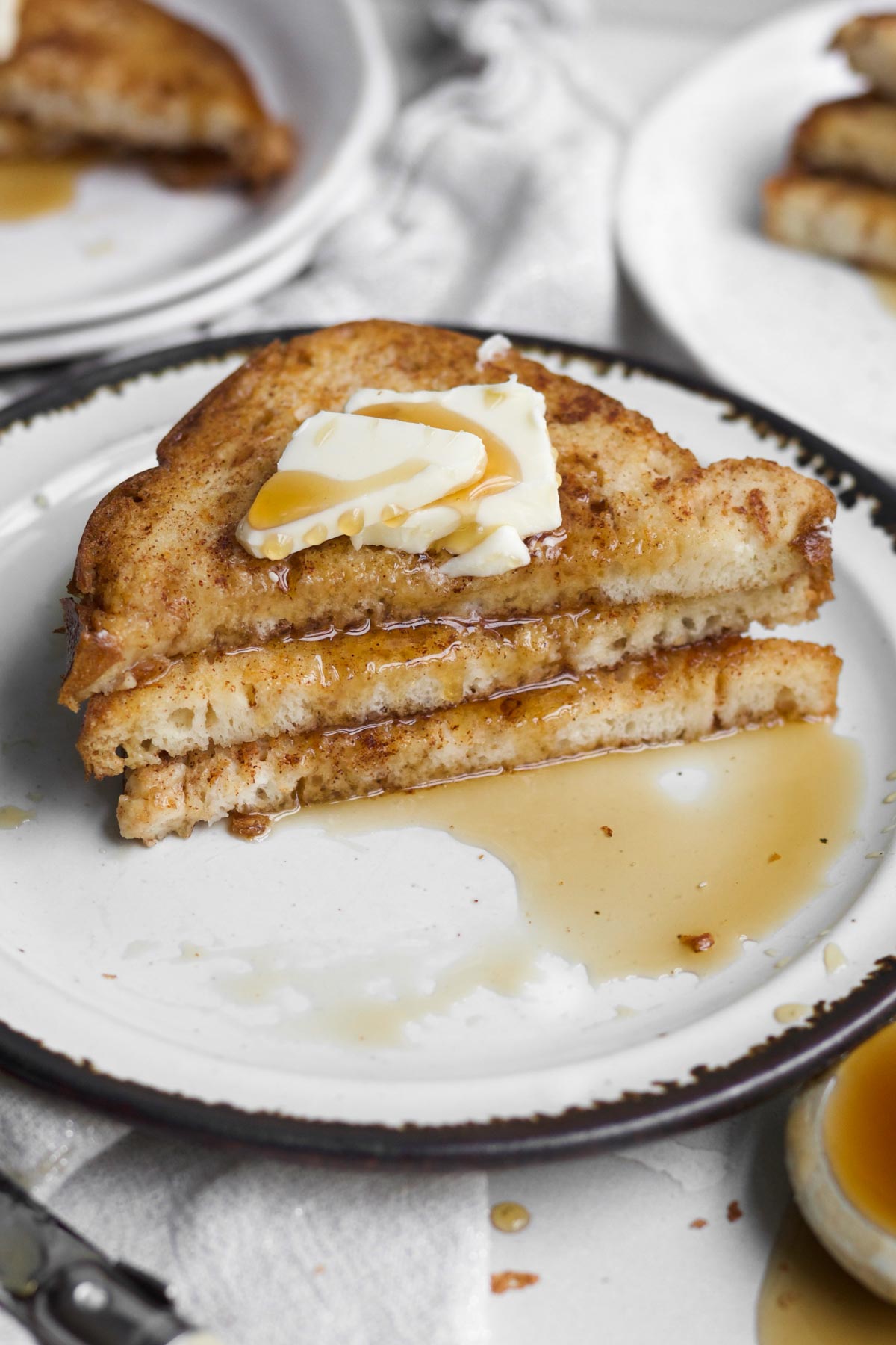 halved stack of easy no egg french toast dripping in sweet maple syrup topped with butter.