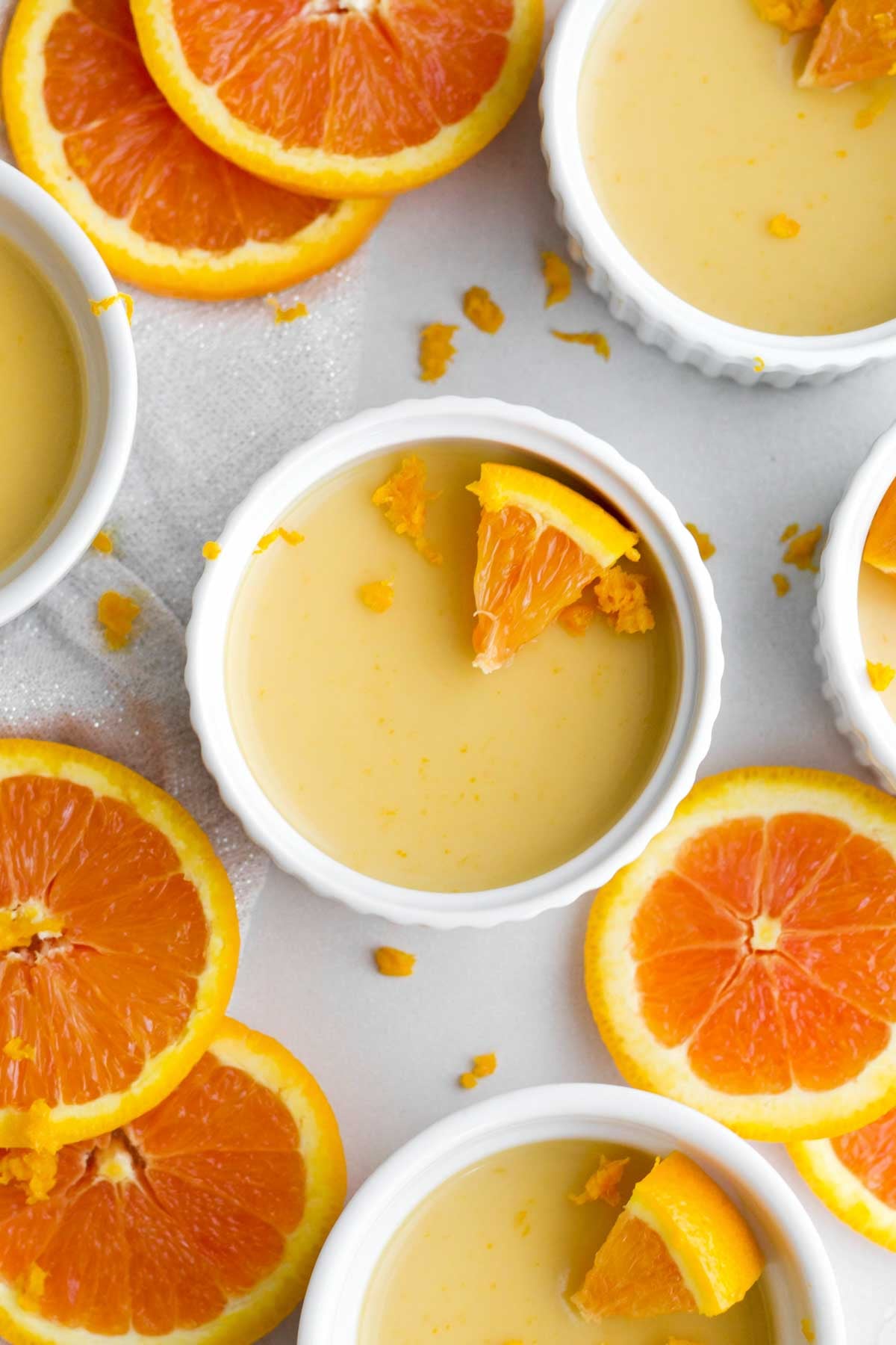 gorgeous gluten-free cups of sweet and citrusy orange posset amongst fresh fruit slices.