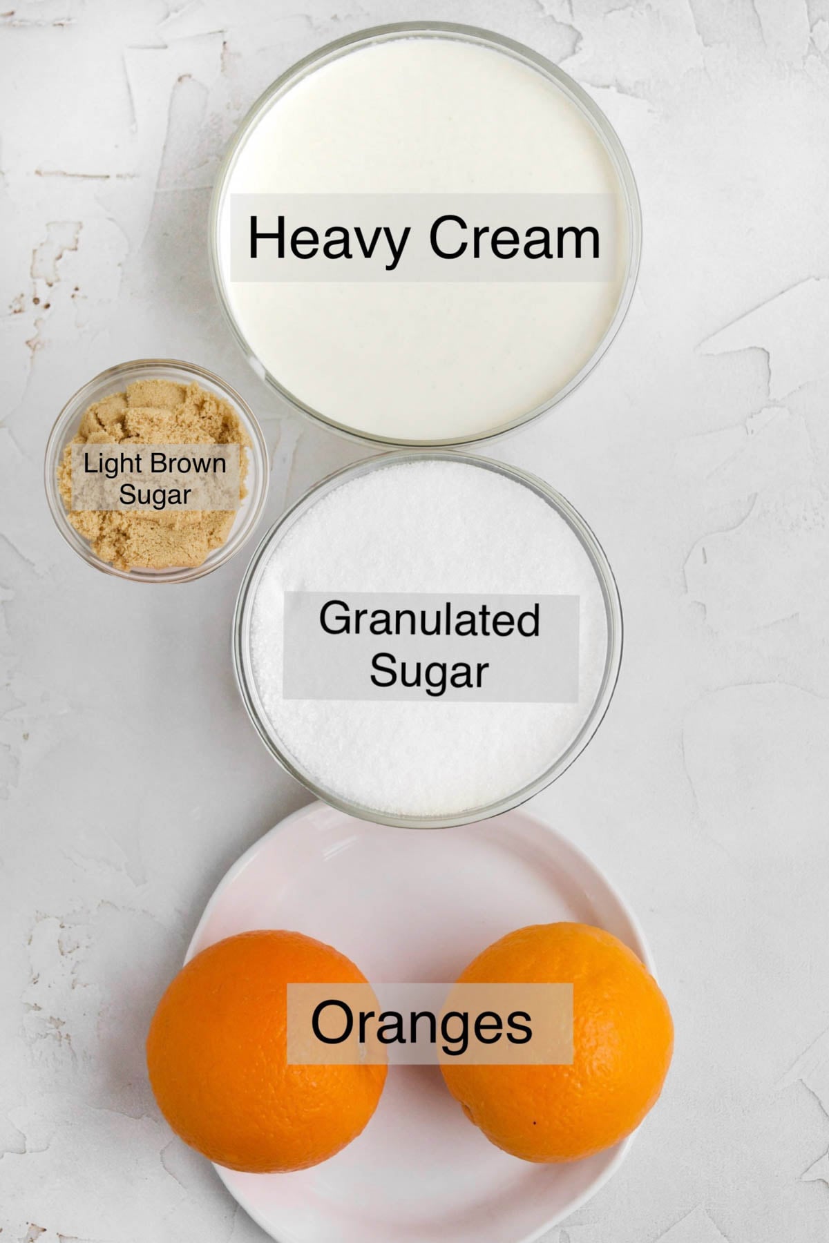 orange posset ingredients in separate bowls: heavy cream, granulated sugar, oranges, and light brown sugar.