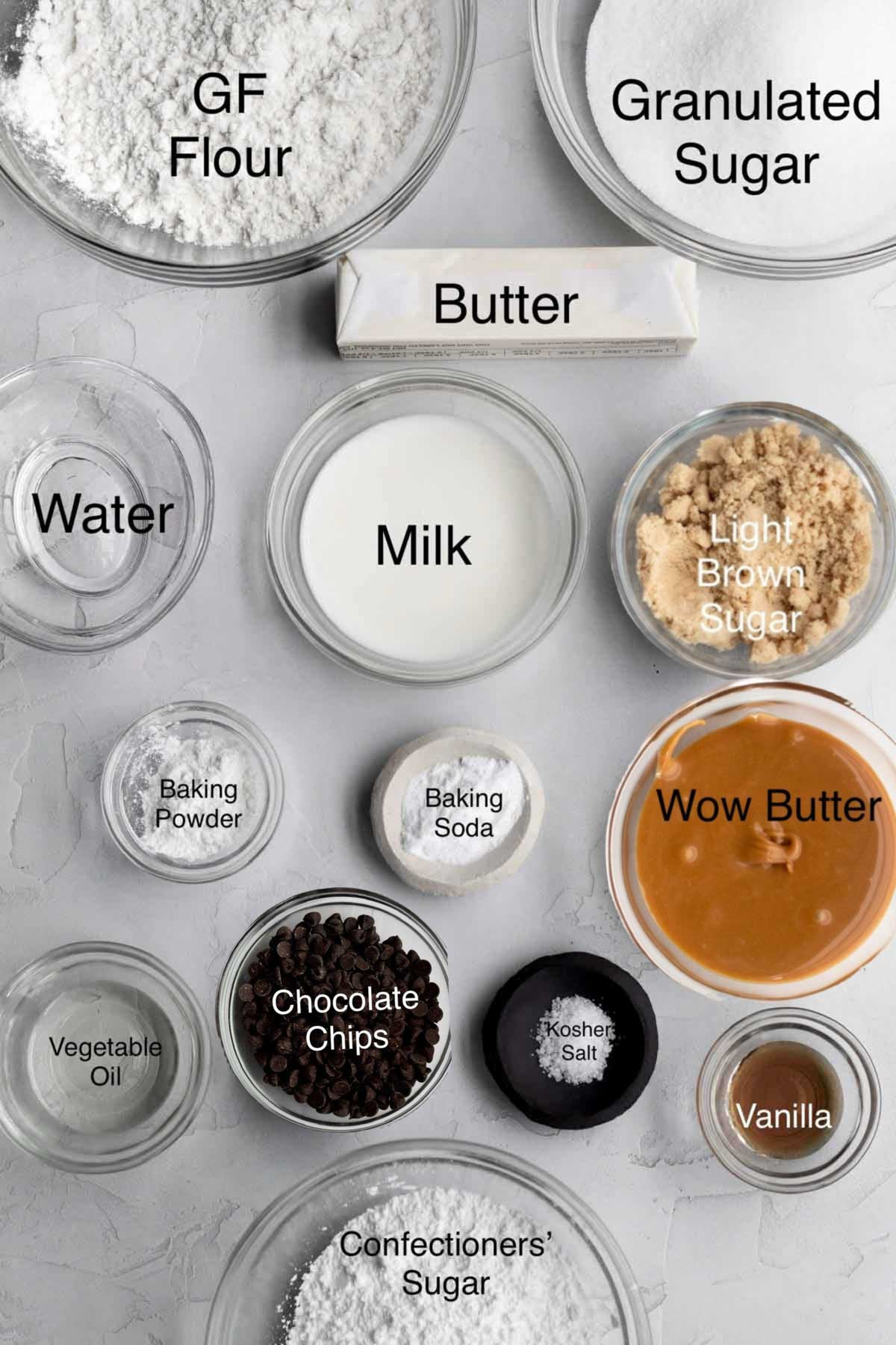 peanut free "peanut butter" cake ingredients in separate containers: gluten free flour, granulated sugar, butter, water, milk, light brown sugar, baking powder, baking soda, wow butter, vegetable oil, chocolate chips, kosher salt, vanilla, and confectioners' sugar.