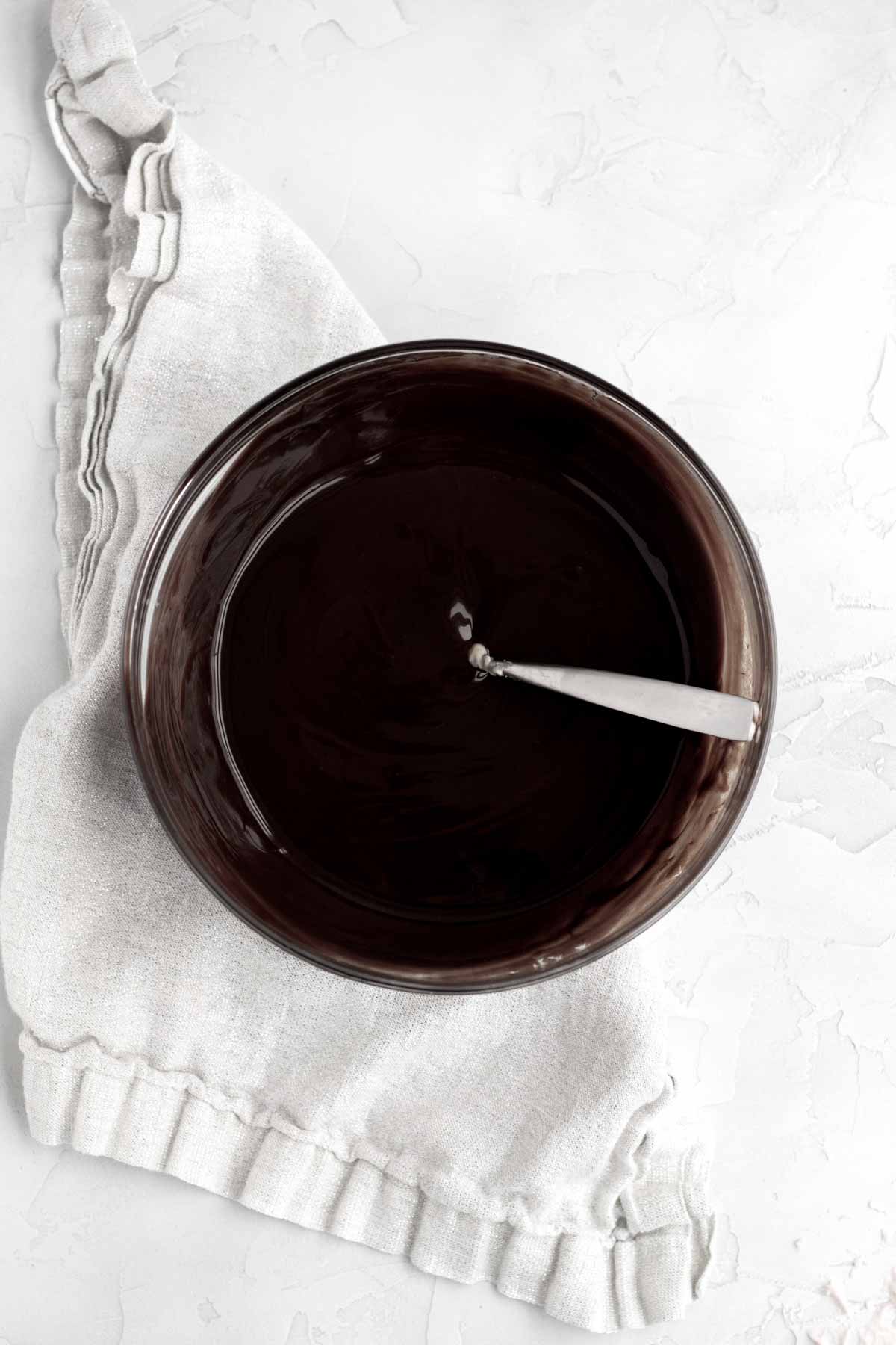 silky dark chocolate ganache in a bowl with a spoon.