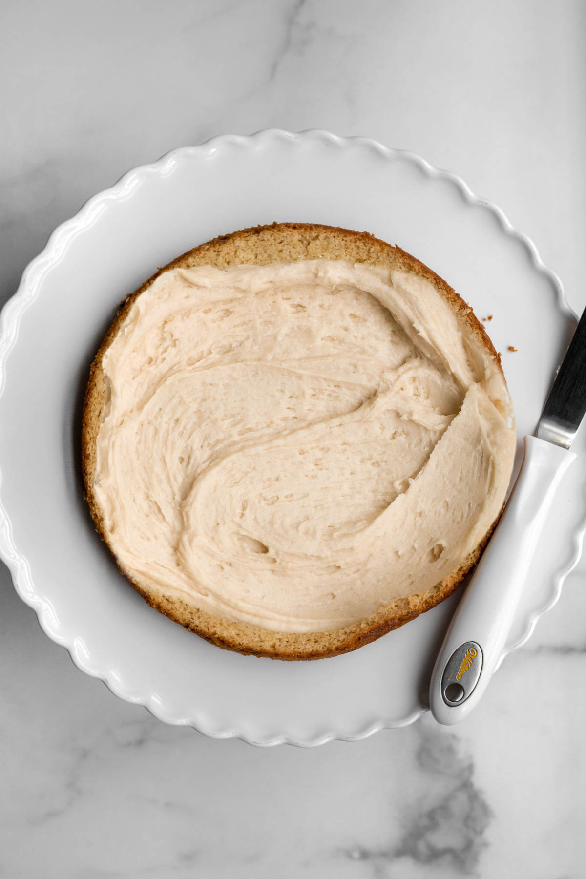 frosting the top of a cake layer with the creamy wow butter frosting.