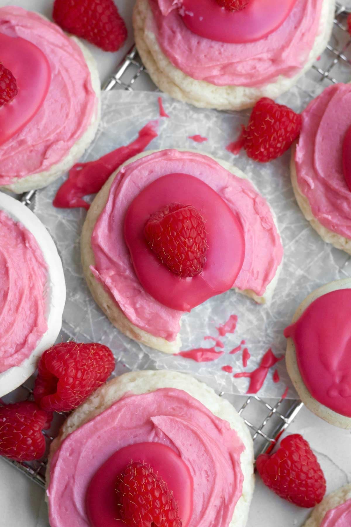 gluten-free raspberry cheesecake cookies topped with bright shades of circular pink layers on parchment paper.