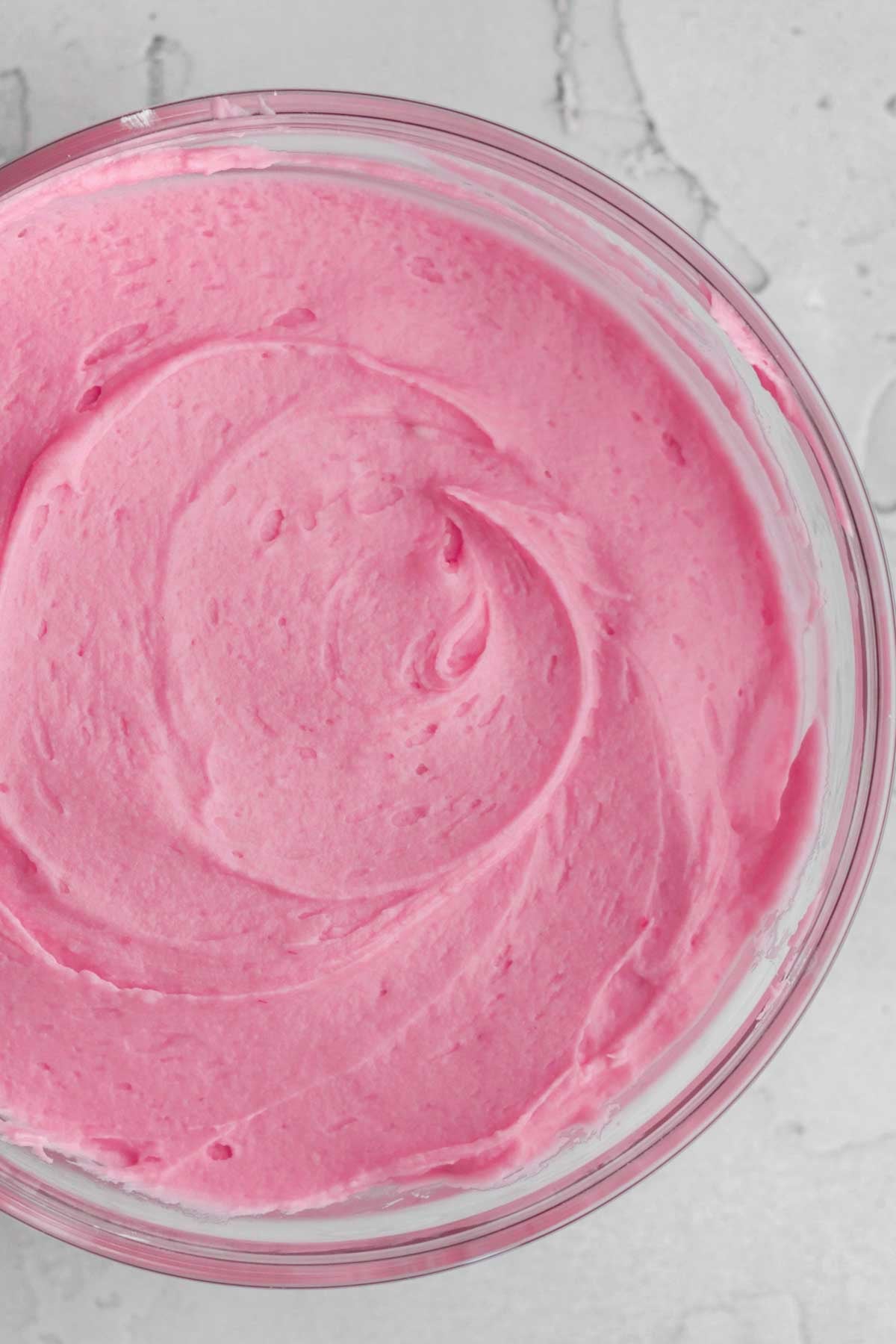 bright pink, creamy raspberry frosting in a bowl.