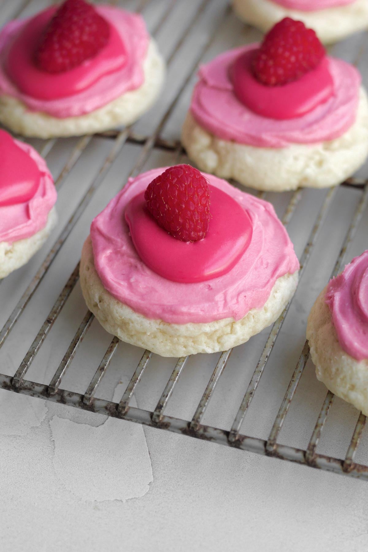 raspberry cheesecake cookies frosted, iced, and topped with a whole fresh raspberry.